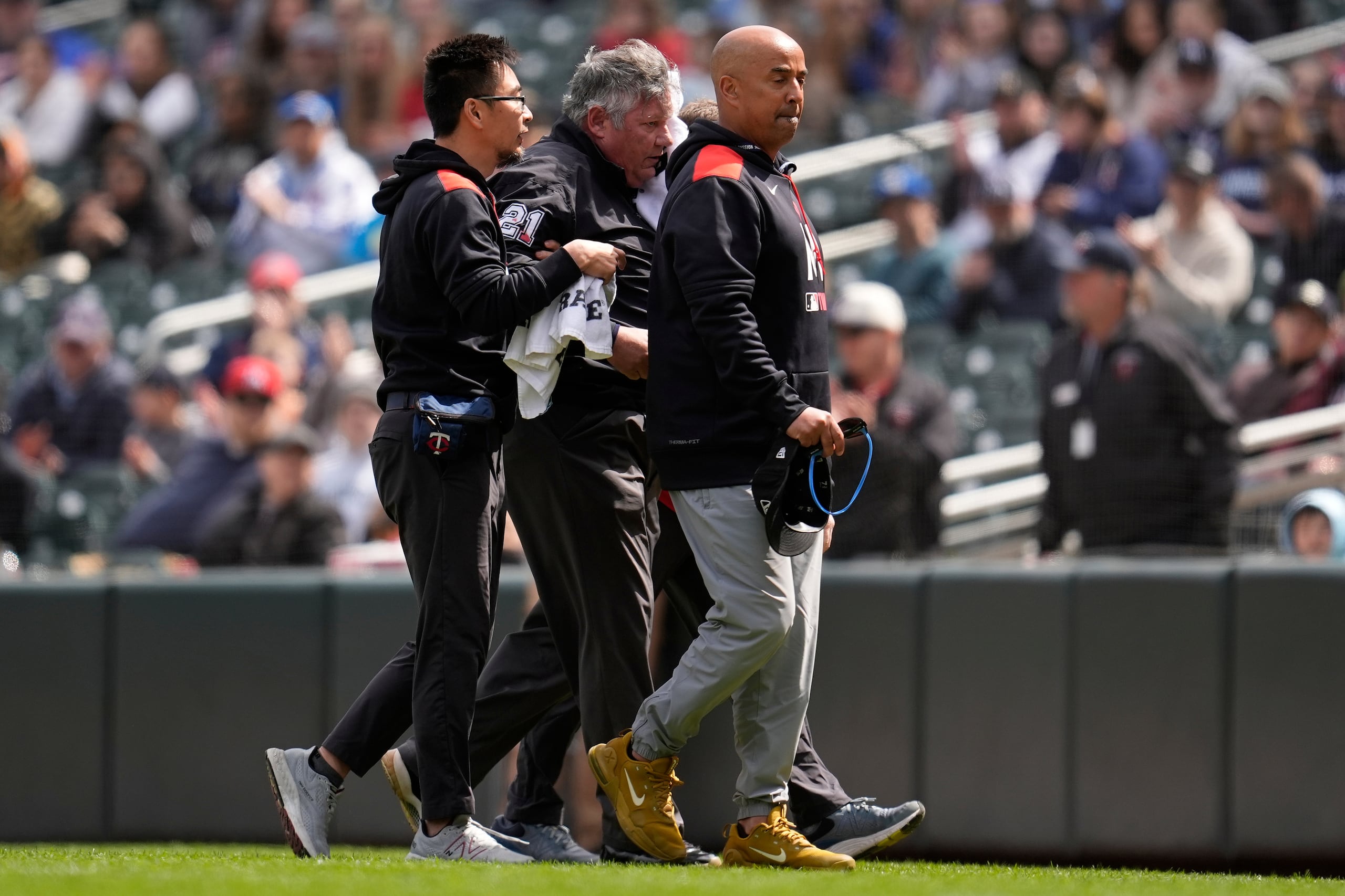 El umpire de primera base Hunter Wendelstedt, centro, camina fuera del campo asistido por personal médico después de recibir un golpe por un batazo de foul durante la séptima entrada del juego de béisbol de Grandes Ligas entre los Twins de Minnesota y los Mets de Nueva York.