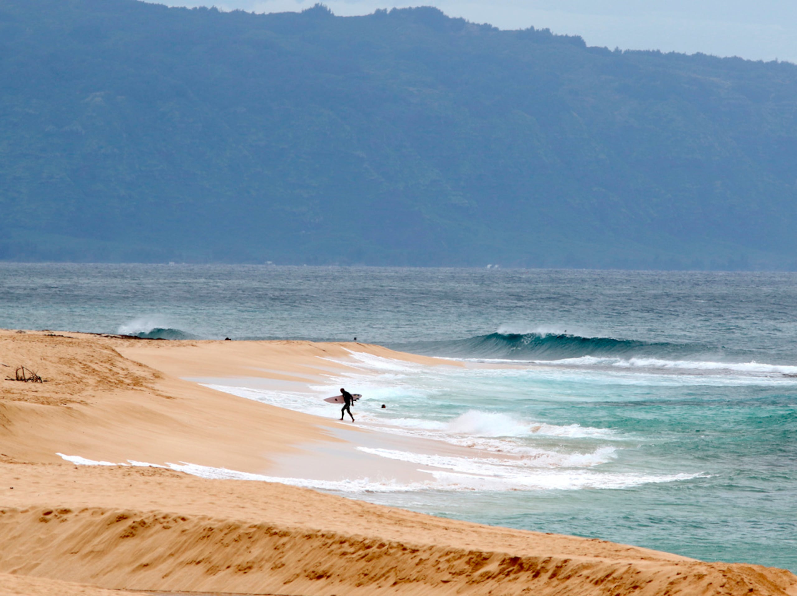 Un surfista sale del agua en la costa norte de Oahu, cerca de Haleiwa, Hawai, el 31 de marzo de 2020.