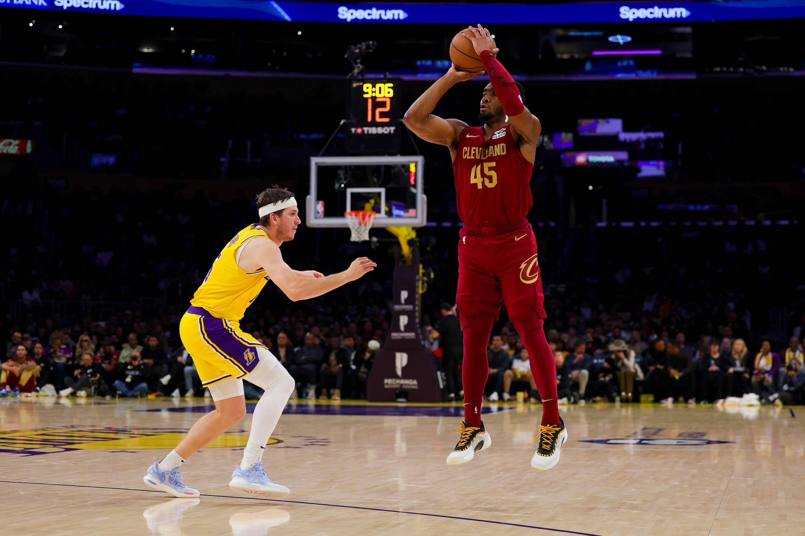 El base de los Cavaliers de Cleveland Donovan Mitchell lanza el balón sobre Austin Reaves de los Lakers de Los Ángeles en el encuentro de la NBA del martes 31 de diciembre del 2024. (AP Foto/Ryan Sun)