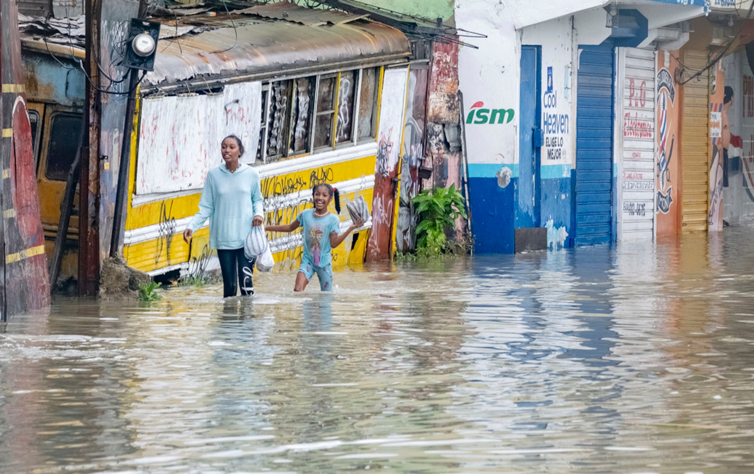 Personas caminan por una calle inundada por las lluvias de la tormenta tropical Franklin, el 22 de agosto de 2023 en Santo Domingo, República Dominicana.