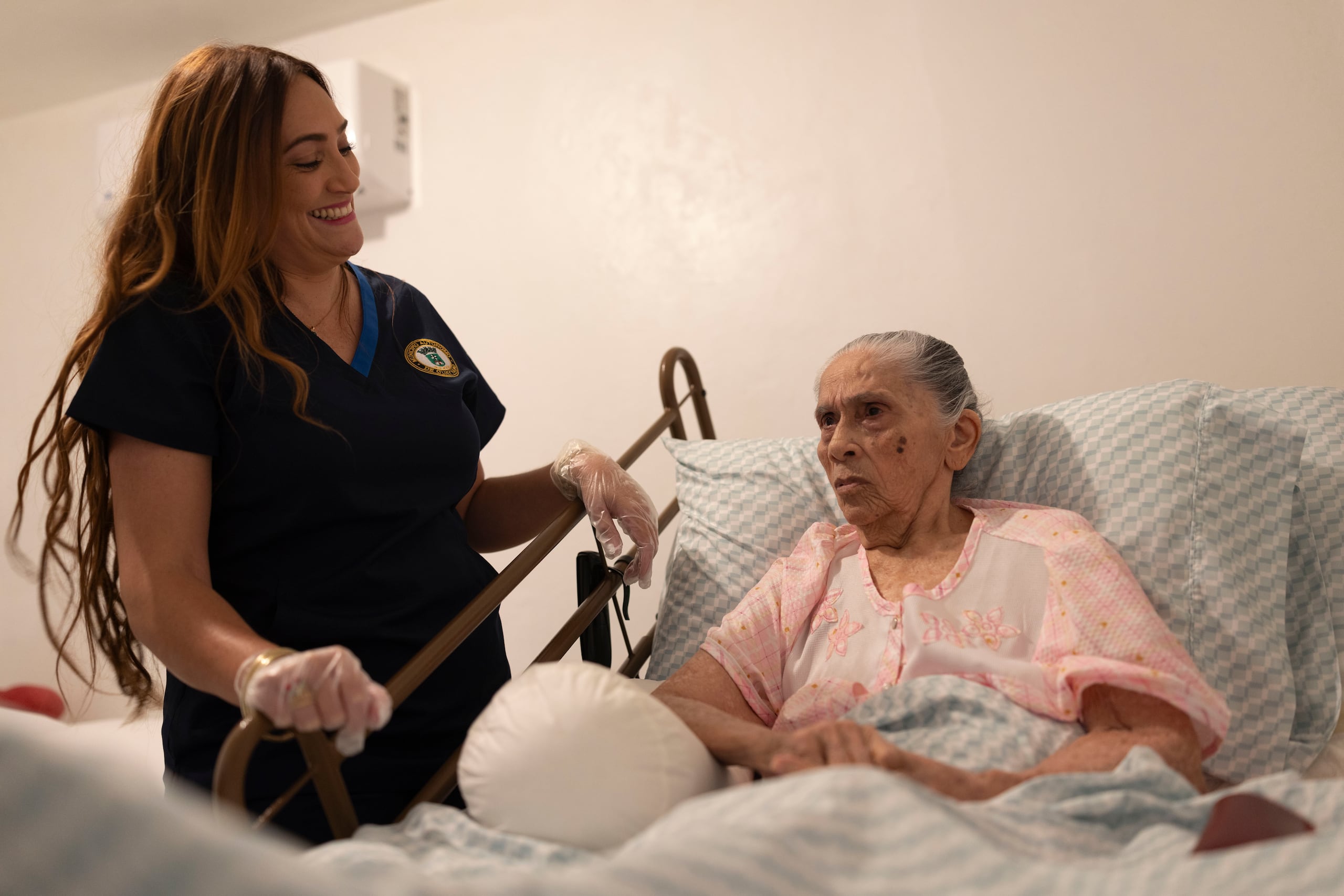 Lisandra Algarín, quien lleva 10 años trabajando con adultos mayores, explica la dinámica que tiene con doña Margarita, a quien asiste en su aseo personal.