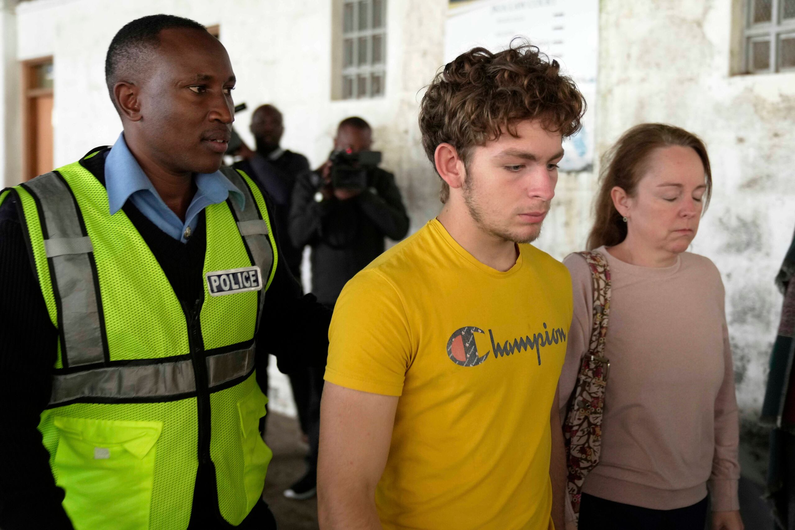 El ciudadano belga Lornoy David, centro, que admitió los cargos relacionados con la posesión ilegal y el tráfico de hormigas reina vivas para venderlas como mascotas exóticas, camina fuera de la Corte Penal del Aeropuerto Internacional Jomo Kenyatta en Nairobi, Kenia el miércoles 23 de abril de 2025. (AP Foto/Brian Inganga)