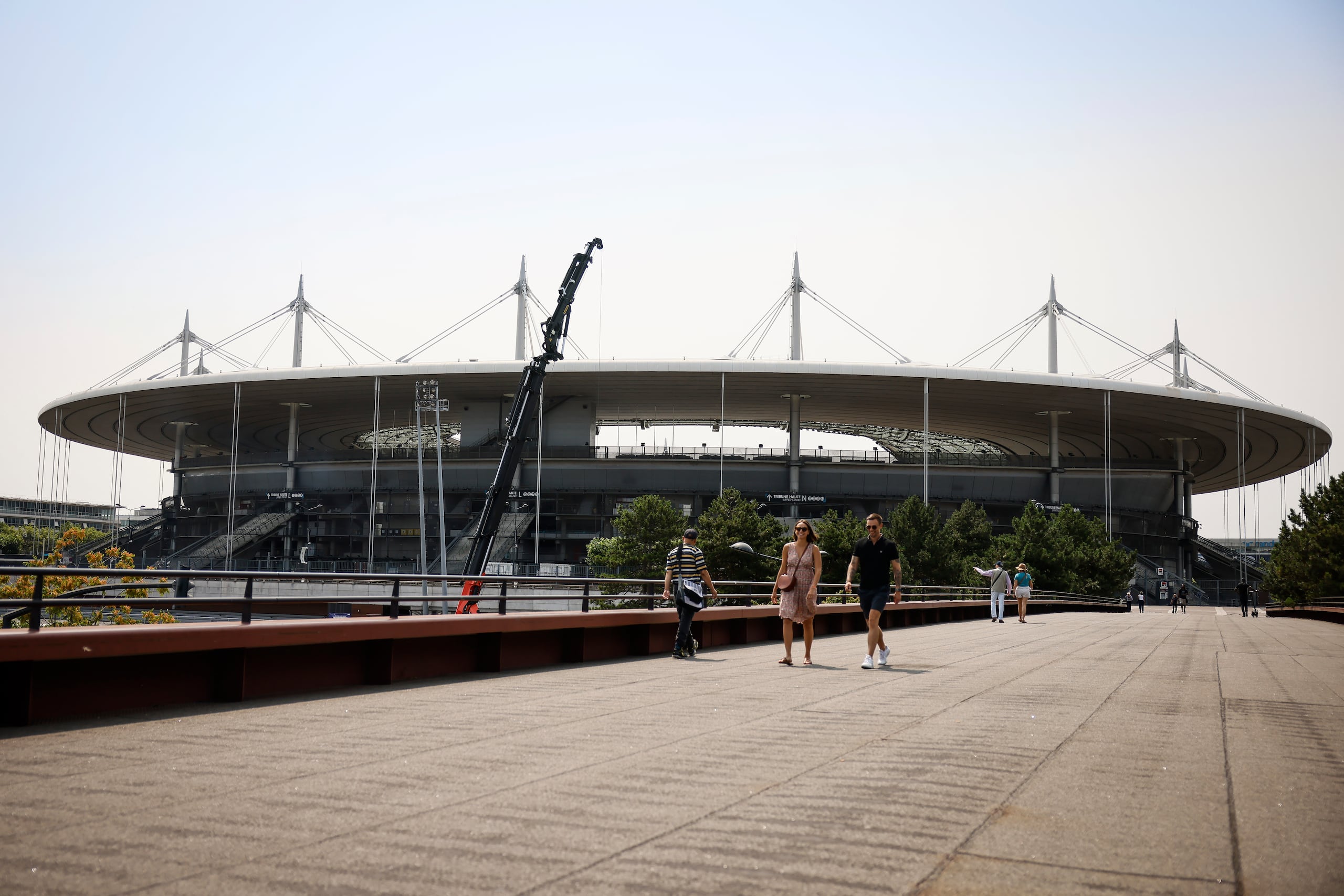 Gente camina cerca del Stade de France, el lunes 10 de julio de 2023 en Saint-Denis. El estadio será la sede del atletismo y el rugby de siete en los Juegos Olímpicos de París 2024. (AP Foto/Thomas Padilla)