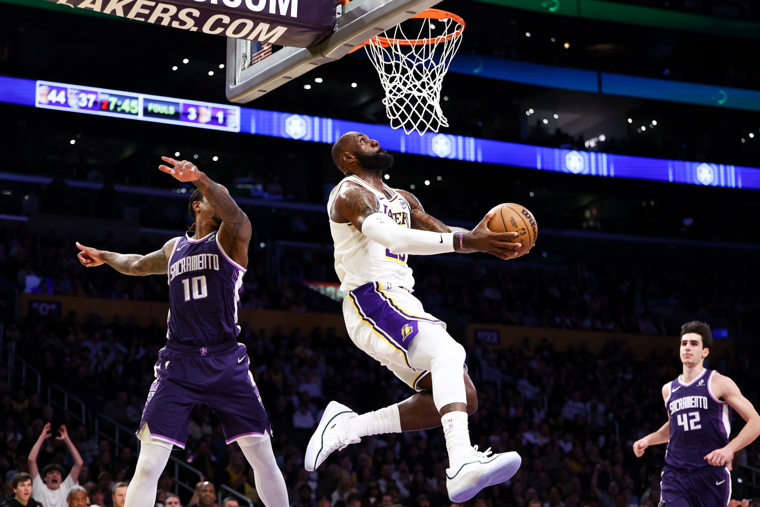 Lebron James, centro, de los Lakers de Los Ángeles, prepara un enceste mientras Demar Derozan (10) y Maxime Raynaud (42), de los Kings de Sacramento, observan durante la primera mitad del juego de baloncesto de la NBA, el domingo 28 de diciembre de 2025, en Los Ángeles. (AP Foto/Jessie Alcheh)