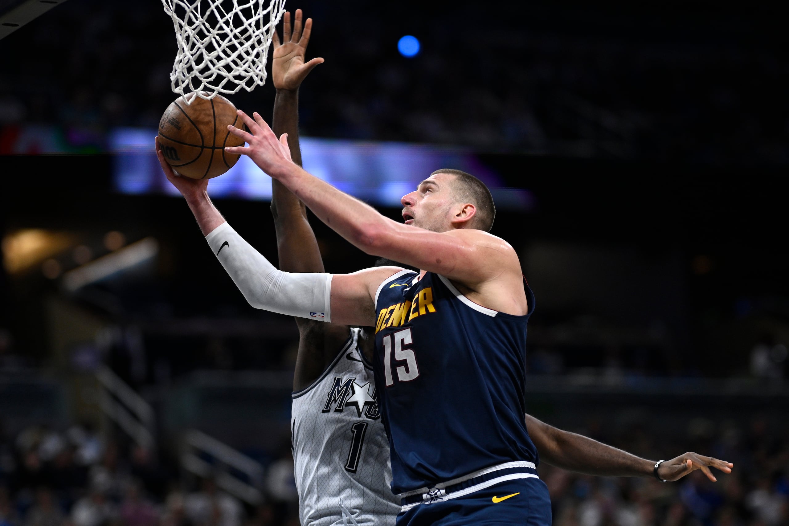 El pívot de los Nuggets de Denver Nikola Jokic (15) brinca para encestar frente al alero del Magic de Orlando Jonathan Isaac (1) durante la primera mitad de un partido de baloncesto de la NBA, el domingo 19 de enero de 2025, en Orlando, Florida (AP Foto/Phelan M. Ebenhack)