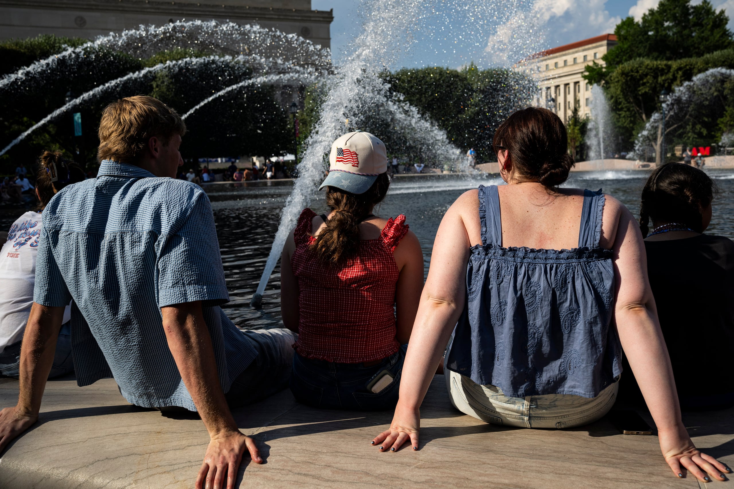 Personas se refrescan en la fuente del Jardín de Esculturas de la Galería Nacional de Arte, en el National Mall de Washington, DC (EE.UU.), durante temperaturas de calor extremo. EFE/GRAEME SLOAN