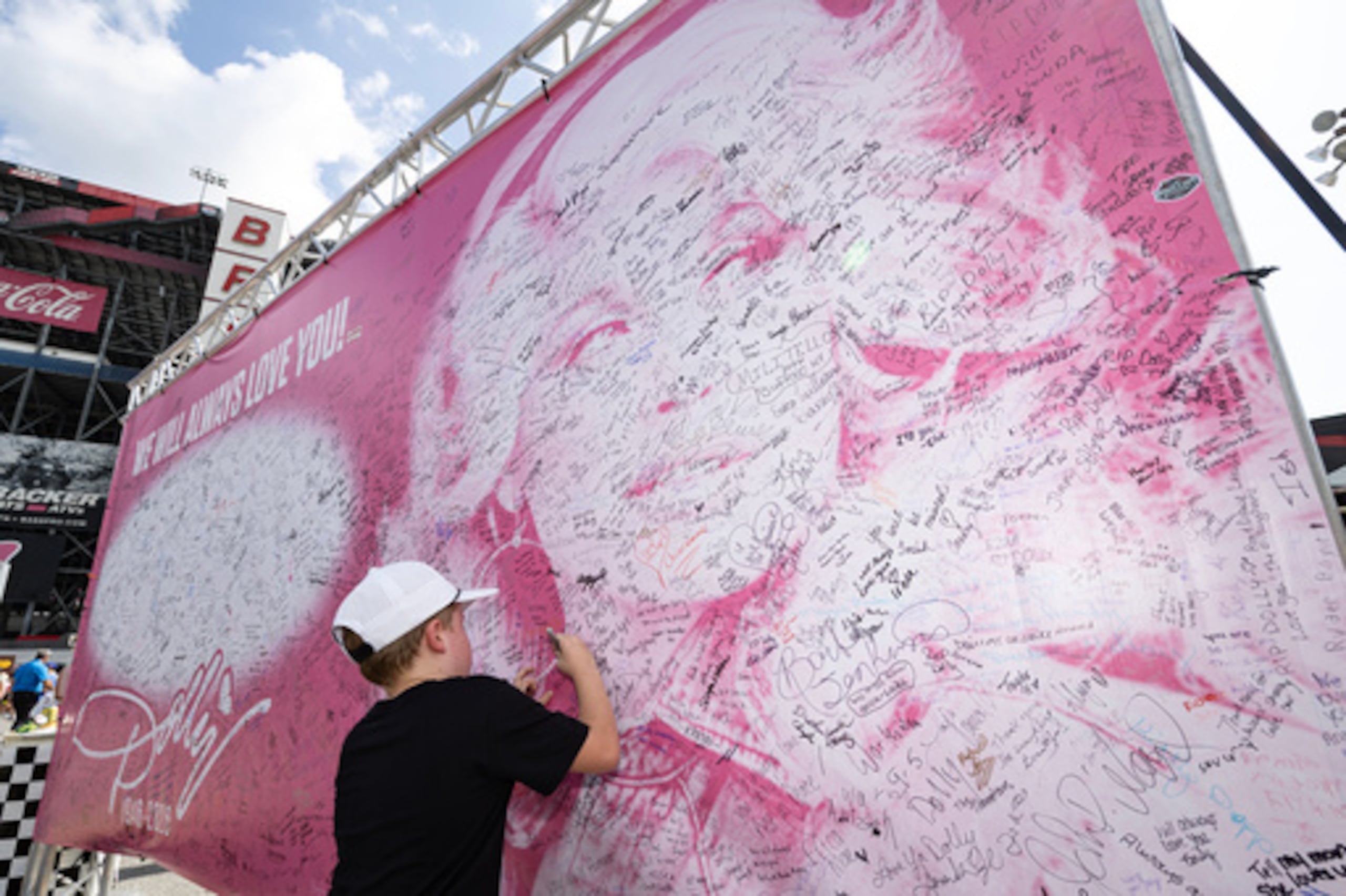 Henry Bailey, de 7 años, de Kentucky, firma un cartel en homenaje a la fallecida Dolly Parton antes de una carrera de la NASCAR Cup Series el sábado 19 de septiembre de 2026 en Bristol, Tennessee. (Foto AP/Wade Payne)