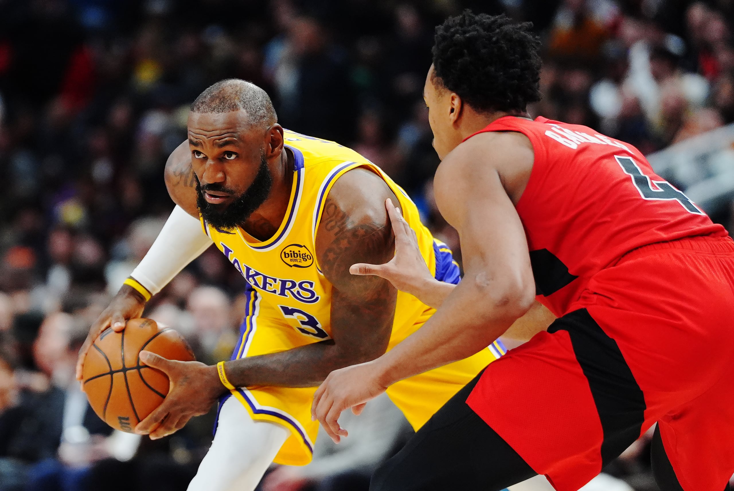 LeBron James, de los Lakers de Los Ángeles, es defendido por Scottie Barnes, de los Raptors de Toronto.