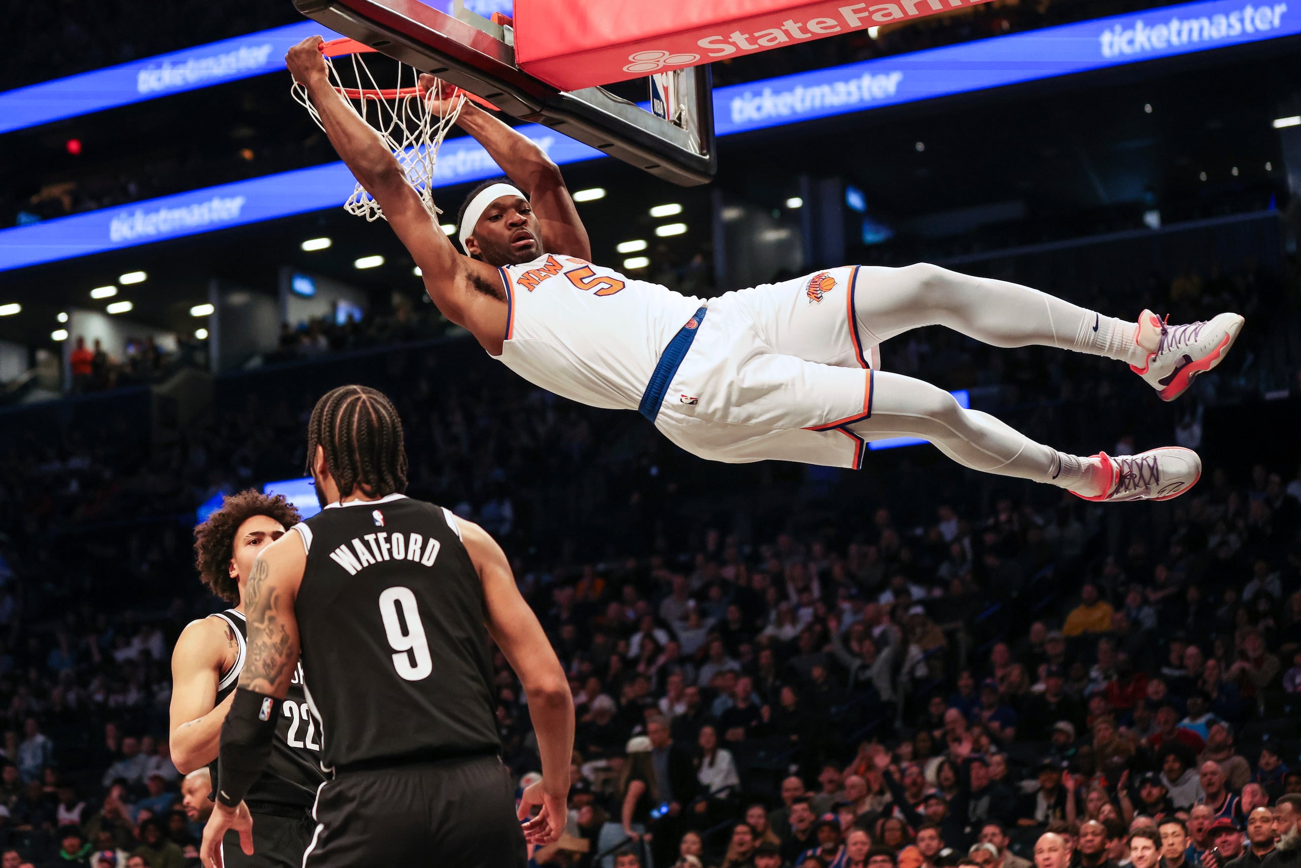 El alero de los Knicks de Nueva York Precious Achiuwa clava el balón frente a Jalen Wilson y Trendon Watford de los Nets de Brooklyn en el encuentro del domingo 13 de abril del 2025. (AP Foto/Heather Khalifa)