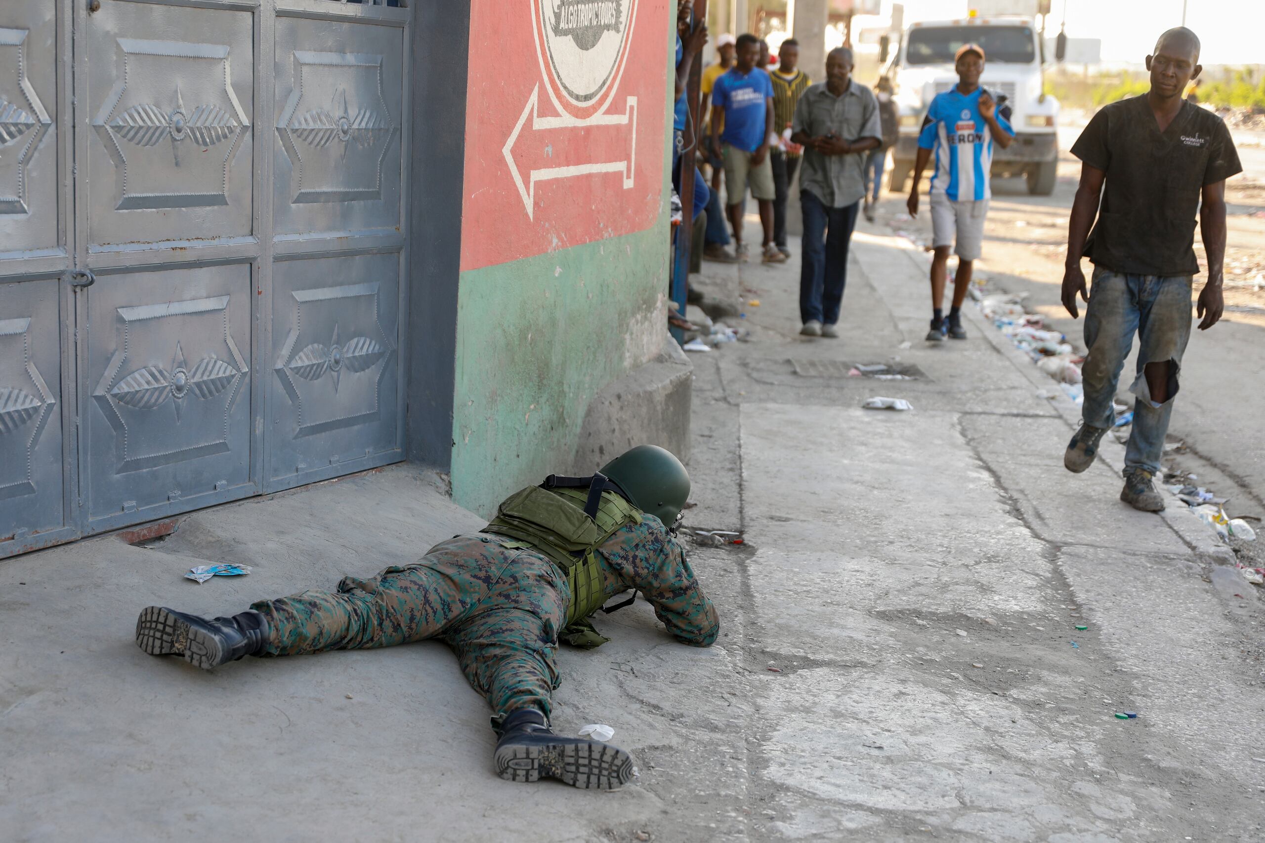 Peatones caminan junto a un soldado que monta guardia en la zona del aeropuerto internacional de Puerto Príncipe, Haití, 4 de marzo de 2024. (AP Foto/Odelyn Joseph)