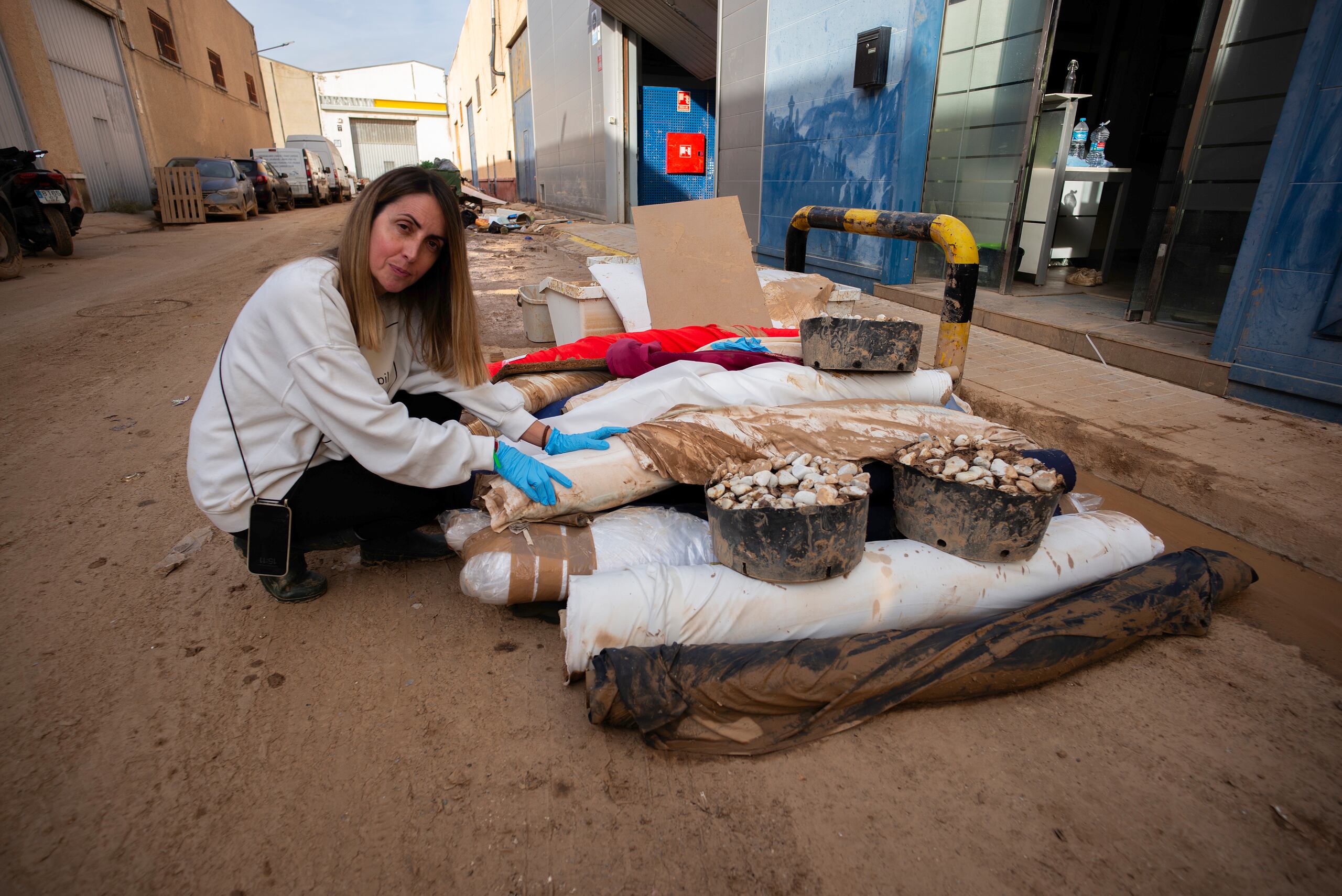 Inma Lorente, copropietaria de una empresa de moda infantil, junto a telas manchadas de barro a causa de las fuertes lluvias torrenciales en la localidad valenciana de Aldaia (España). EFE/ Jorge Zapata.