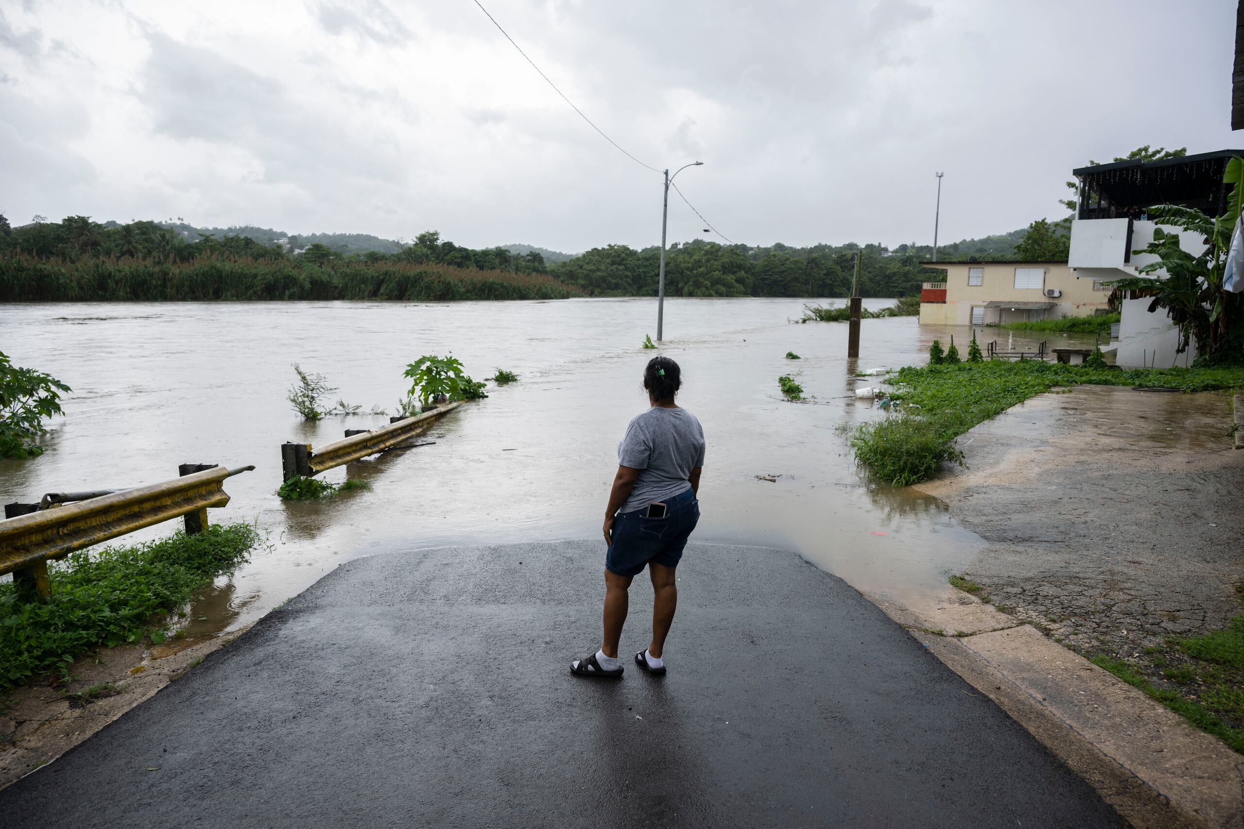 Carmen Santiago frente a la calle inundada en su comunidad.