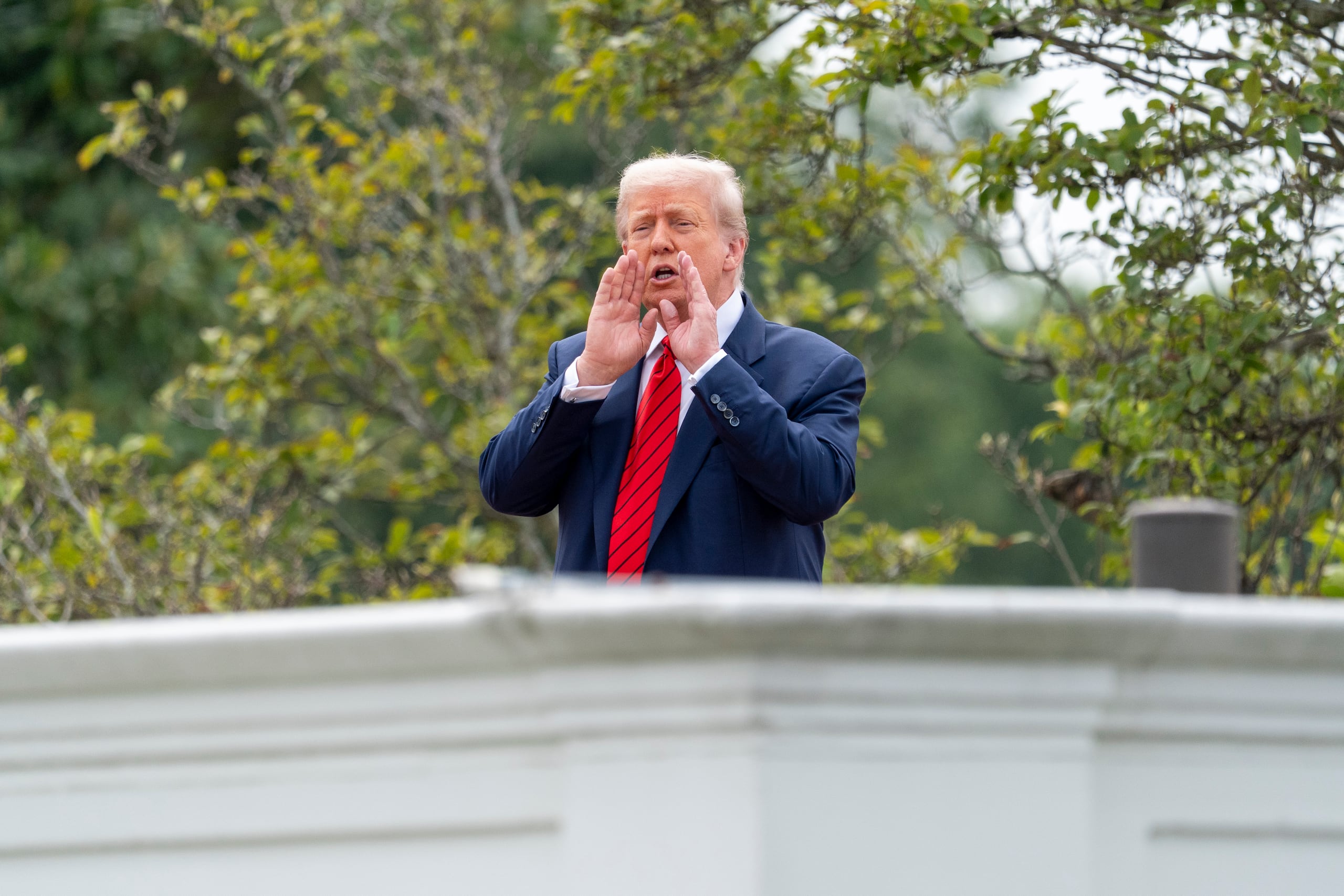 El presidente Donald Trump grita a los reporteros mientras inspecciona los terrenos desde el techo arriba de la columnata que va hacia el Ala Oeste de la Casa Blanca, el martes 5 de agosto de 2025, en Washington. (AP Foto/Alex Brandon)