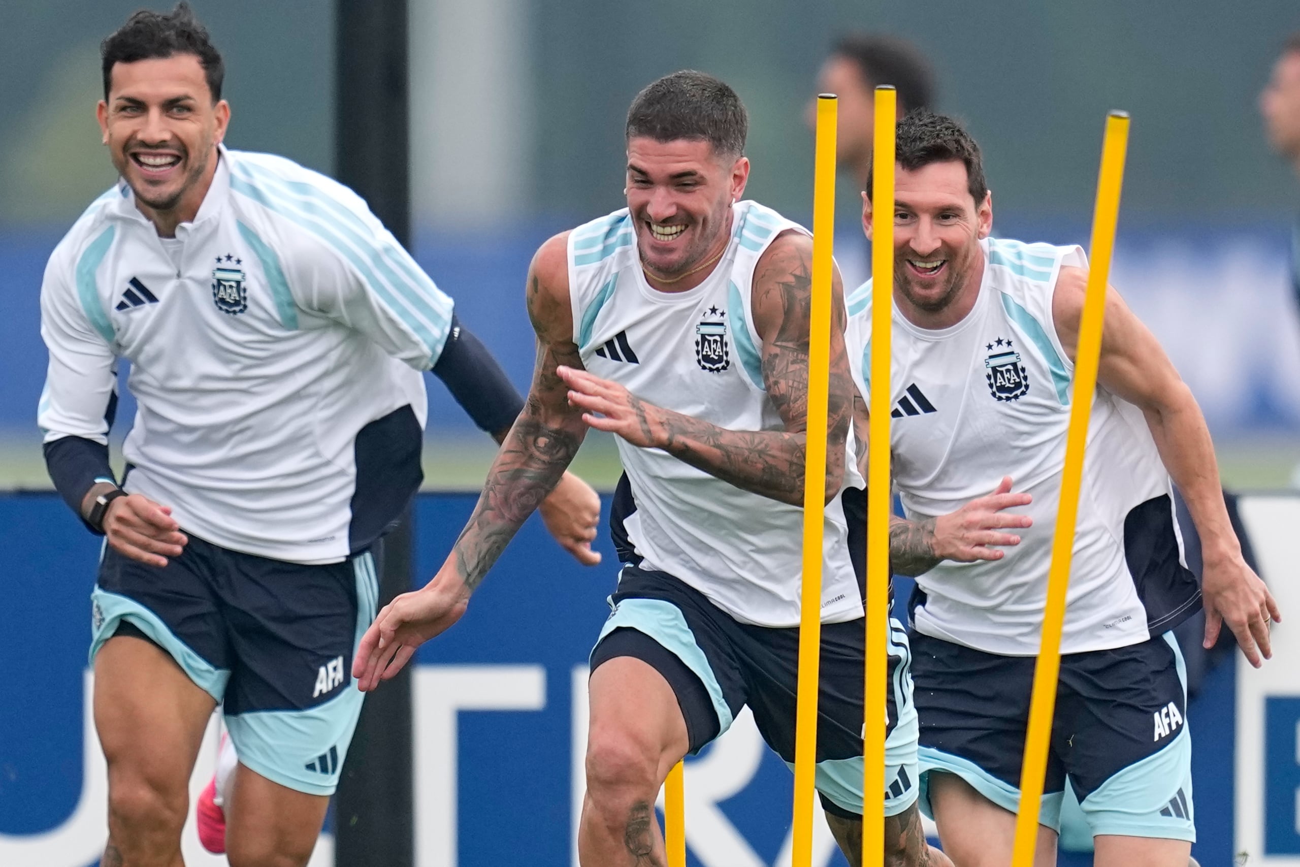Lionel Messi, Rodrigo Javier De Paul y Leandro Paredes, desde la derecha a la izquierda, sonríen durante un entrenamiento para el partido final de este domingo.