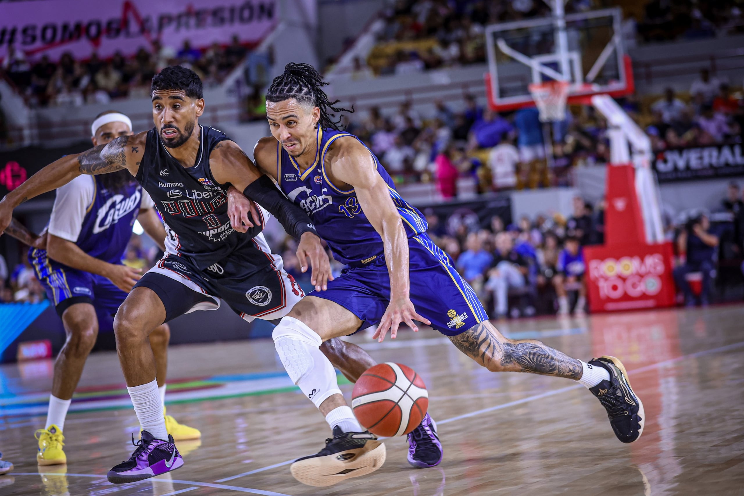 Travis Trice, de los Criollos, maneja el balón contra Jezreel de Jesús, de los Leones, en el primer juego de semifinal del BSN.