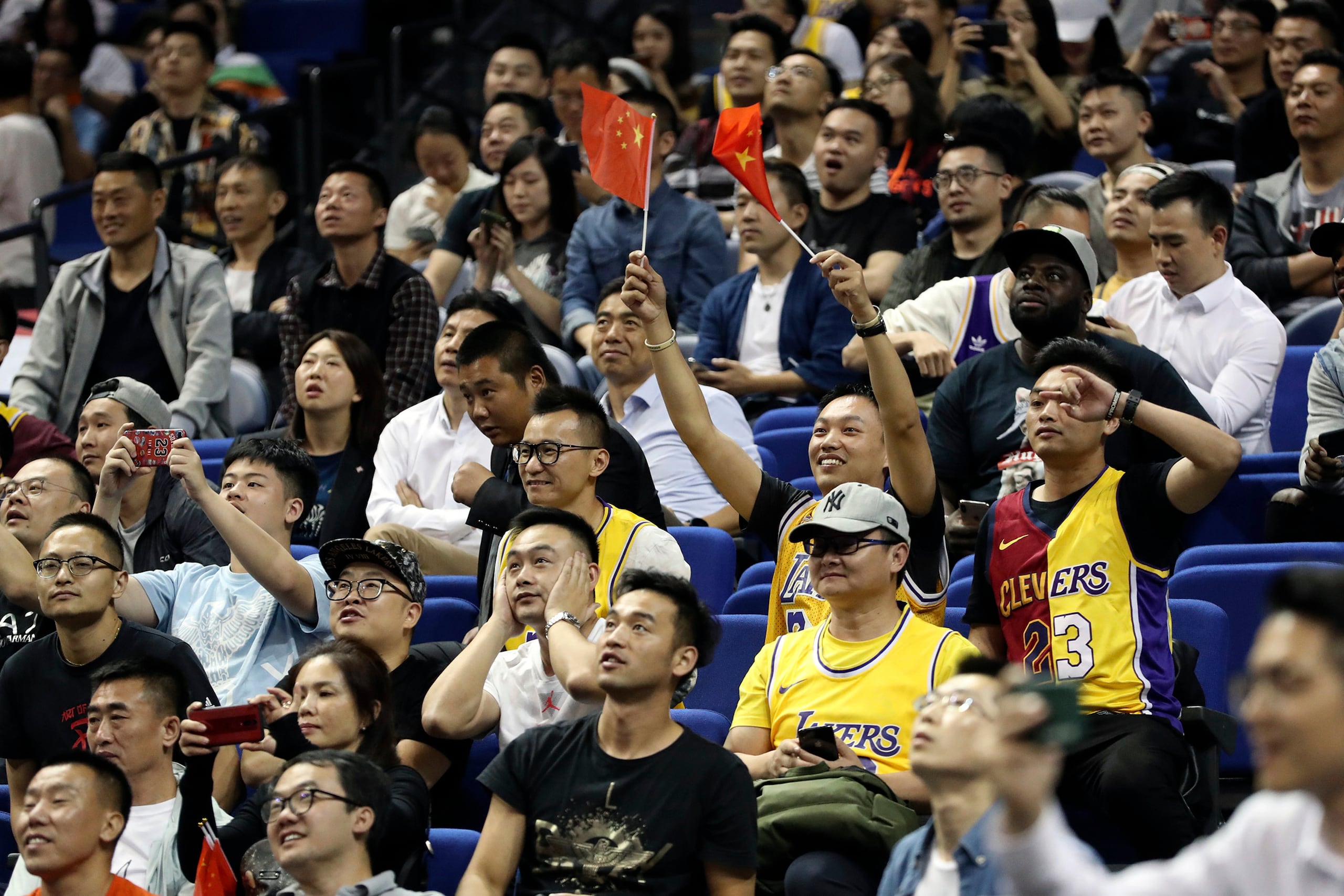 Fanáticos chinos muestran banderas de su país durante un partido entre los Nets de Brooklyn y los Lakers de Los Ángeles en Shanghái, el 10 de octubre de 2019. (AP Foto/archivo)