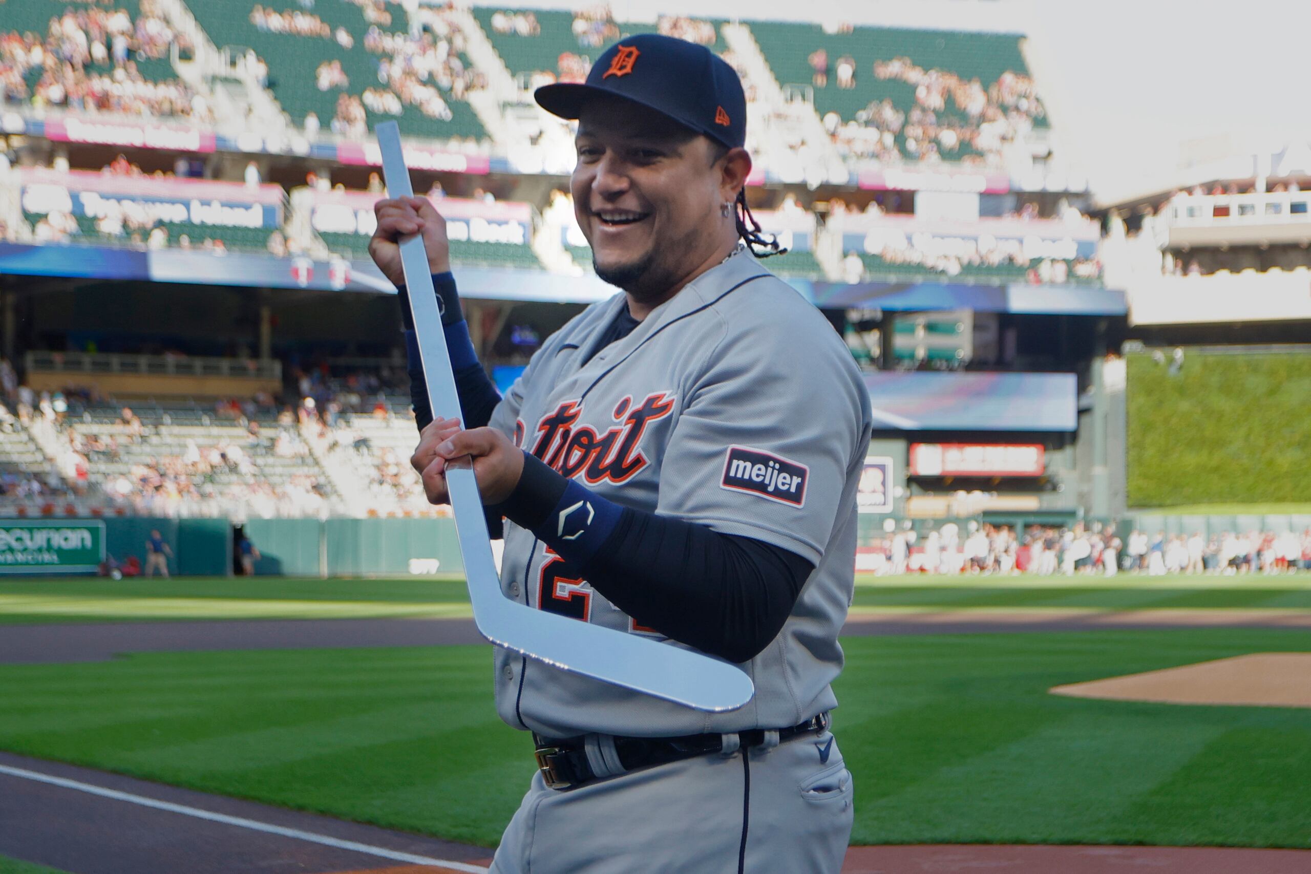 El venezolano Miguel Cabrera, de los Tigers de Detroit, sostiene un bastón de hockey, hecho de plata, que le obsequiaron los Mellizos de Minnesota.