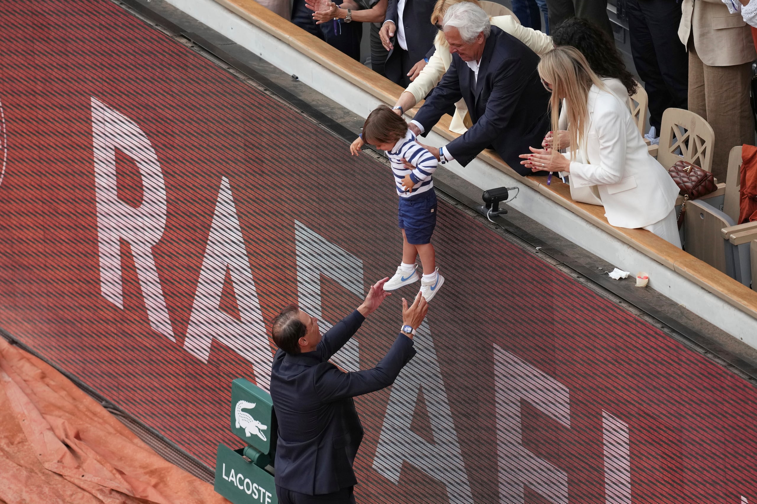 Rafa Nadal levanta sus brazos para alcanzar a su hijo Rafael Junior durante la ceremonia de honra que le realizaron en el Philippe-Chatrier, en el torneo Roland-Garros en París.