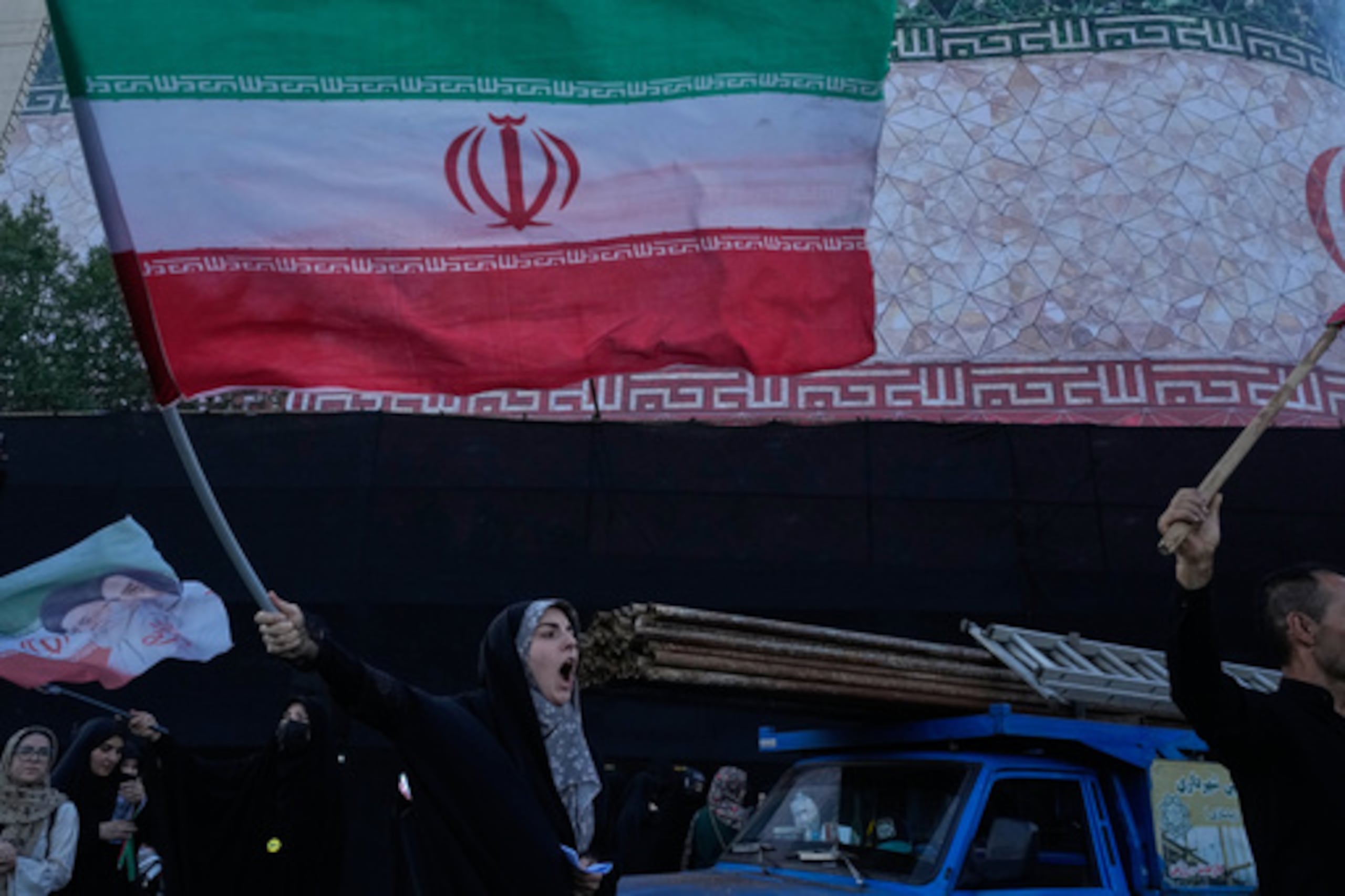 Una mujer agita banderas iraníes mientras corea consignas en contra de las conversaciones entre Irán y Estados Unidos en la plaza de la Revolución Islámica de Teherán, Irán, el domingo 14 de junio de 2026. (Foto AP/Vahid Salemi)