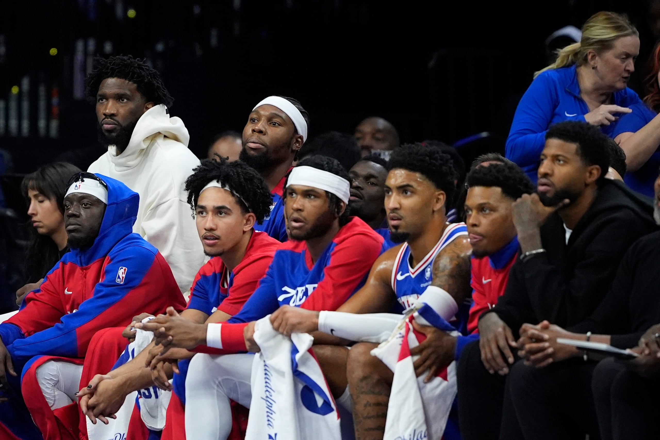 Joel Embiid (fondo a la izquierda) de los 76ers de Filadelfia, observa desde la banca el partido contra los Bucks de Milwaukee.