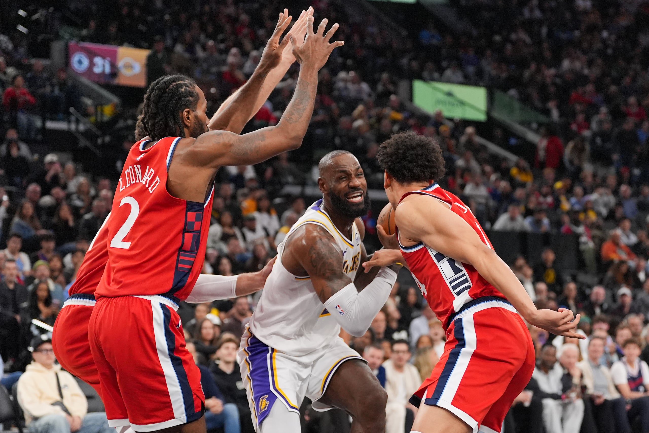 El alero de los Lakers de Los Ángeles, LeBron James, al centro, es defendido por el alero de los Clippers de Los Ángeles, Kawhi Leonard, a la izquierda, y el base Kobe Sanders durante la primera mitad de un juego de baloncesto de la NBA el sábado 20 de diciembre de 2025, en Inglewood, California. (AP Photo/Jae C. Hong)