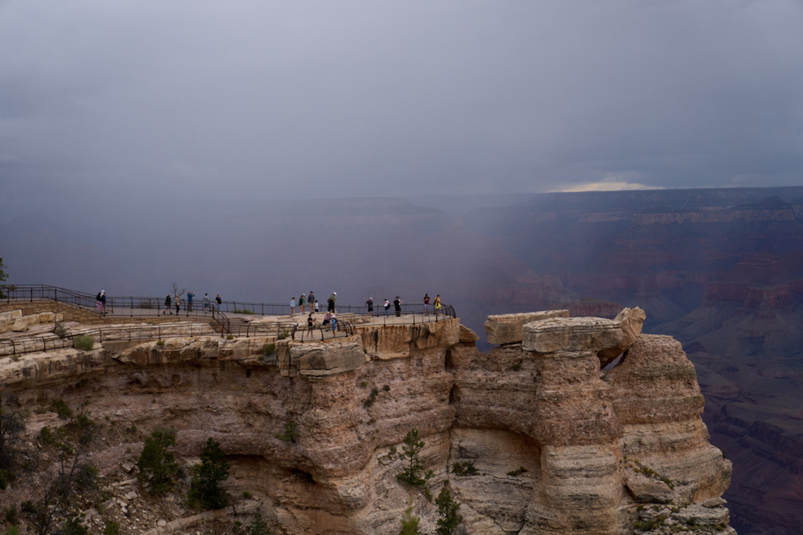 Personas observan desde el borde del Gran Cañón mientras la lluvia avanza hacia el cañón, el lunes 31 de agosto de 2026, en el Parque Nacional del Gran Cañón, Arizona.