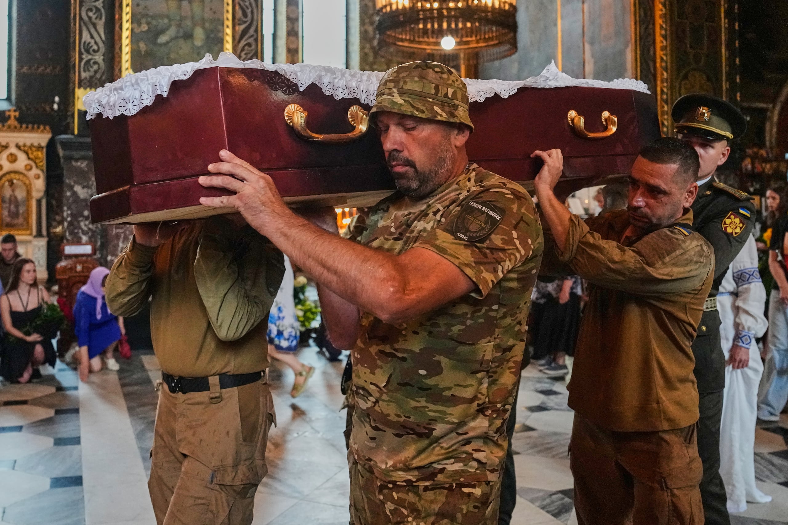 Los compañeros soldados portan el ataúd de Oleksiy Yukov, quien resultó herido de muerte mientras exhumaba los cuerpos de soldados caídos en el frente en la región de Donetsk, durante el servicio fúnebre en la Catedral de San Volodymyr en Kiev, Ucrania, el sábado, 8 de agosto. (Foto AP/Efrem Lukatsky)