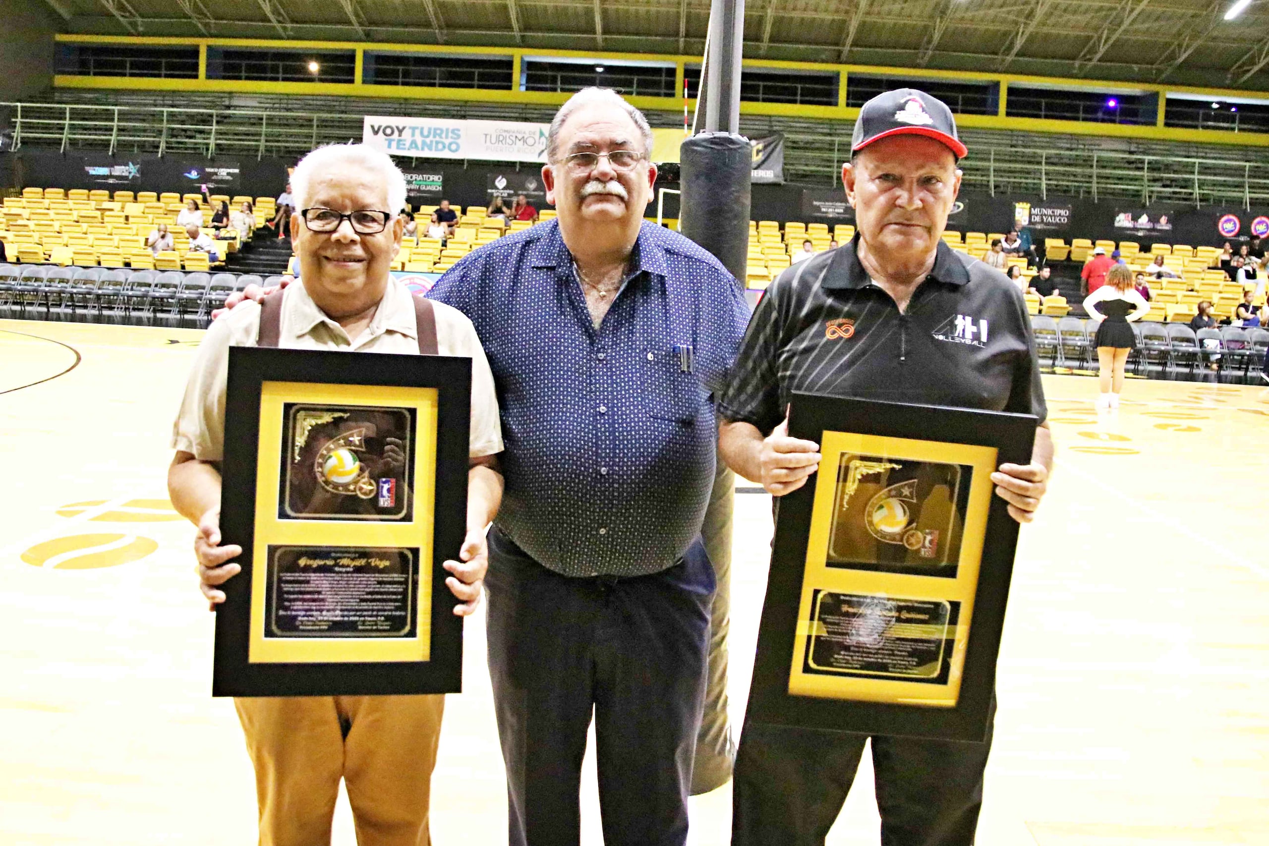 Gregorio “Goyito” Mejill Vega, a la izquierda, y Francisco “Frankie” Santana Quiñónez, a la derecha, aparecen acompañados por el presidente de la Federación de Voleibol de Puerto Rico al ser reconocidos en la dedicatoria del torneo 2025 de la Liga de Voleibol Superior Masculino.