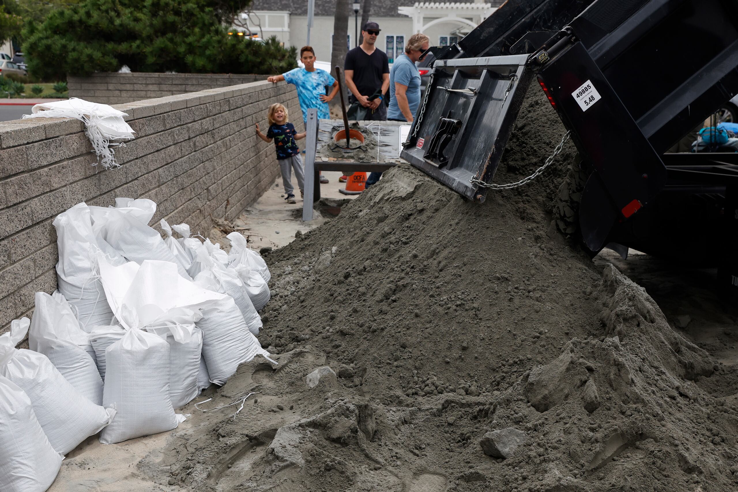 Un camión arroja arena en una estación de bomberos local donde los residentes pueden llenar bolsas de arena para ayudar a fortalecer sus hogares, en Seal Beach, California.