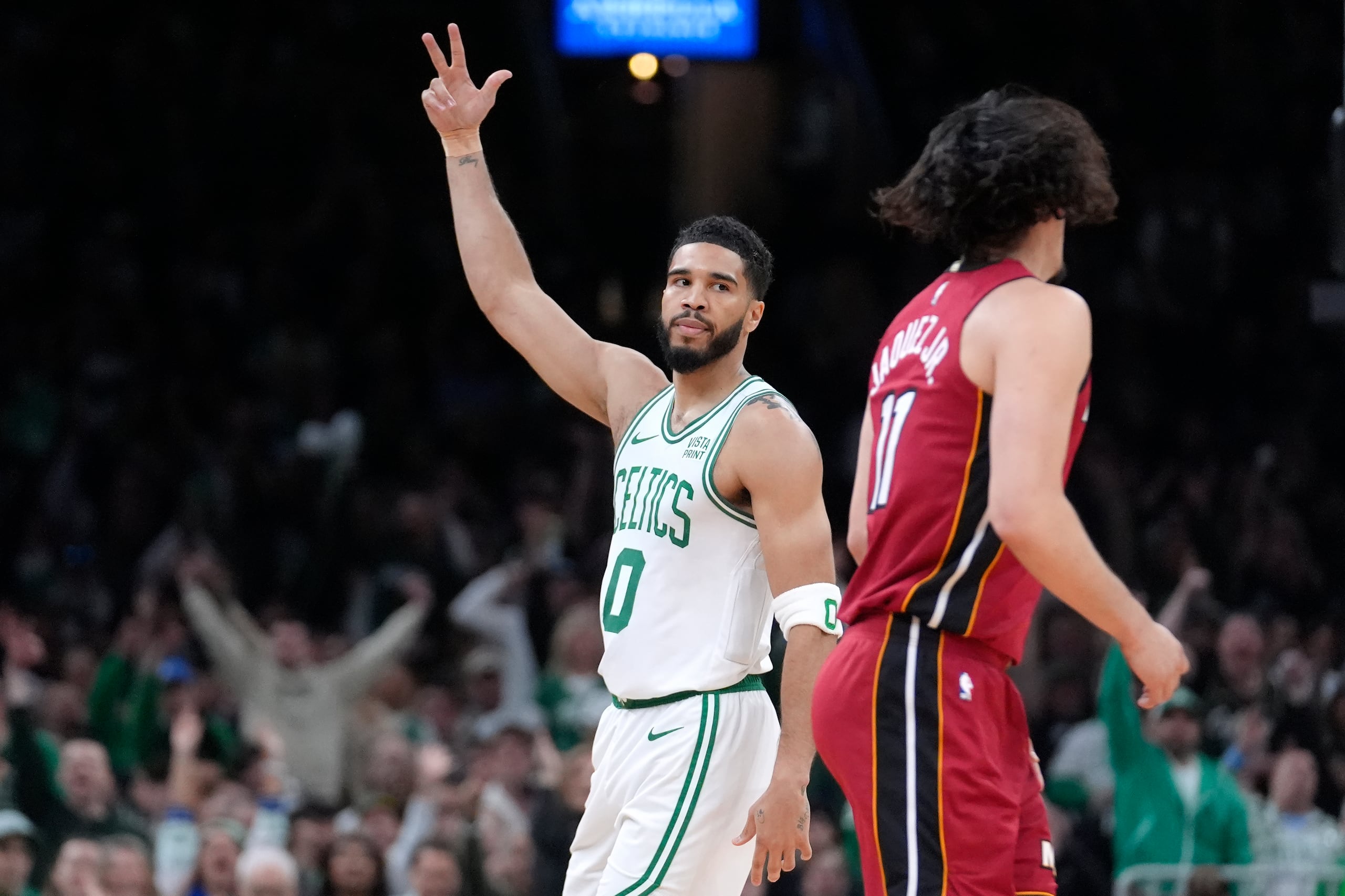 El alero de los Celtics de Boston Jayson Tatum (0) celebra frente al armador mexicano del Heat de Miami Jaime Jaquez Jr. (11), durante la primera mitad del Juego 1 de la serie de primera ronda de postemporada de la NBA, el domingo 21 de abril de 2024, en Boston.