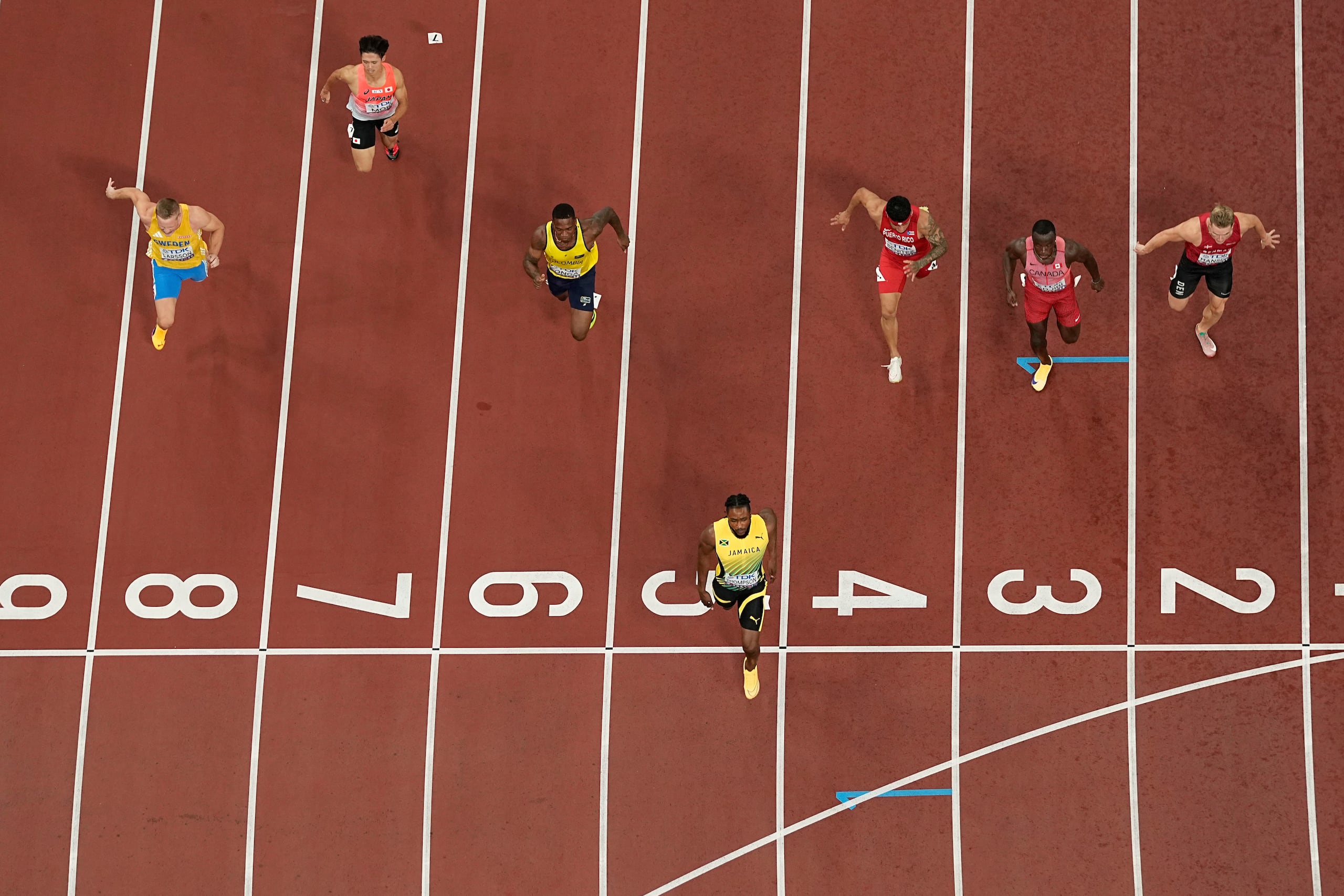 La jamaica Kishane Thompson gana su serie de los 100 metros masculinos, mientras el boricua Eloy Benítez corre en el cuarto carril en el Campeonato Mundial de Atletismo en Tokio.