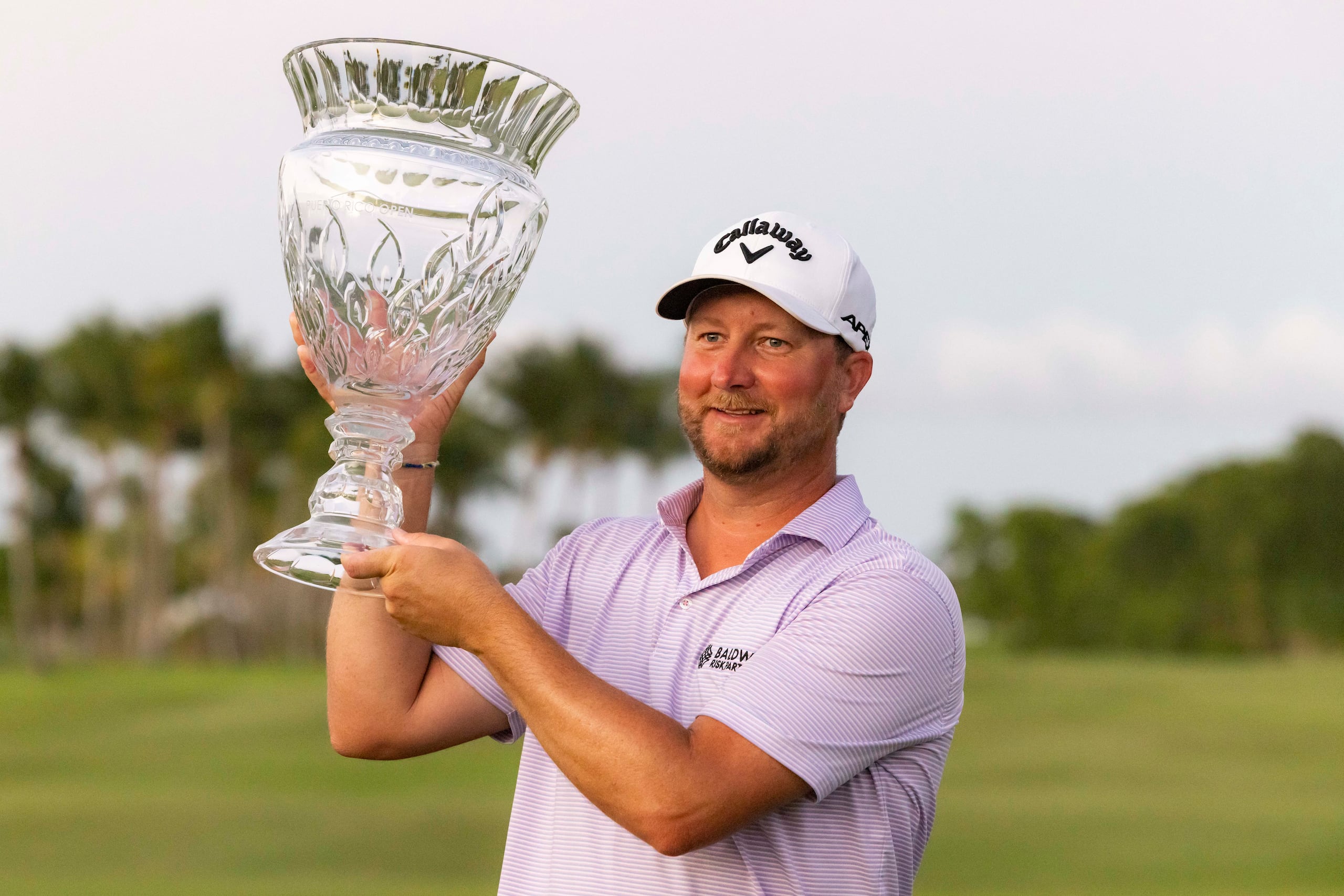 Brice Garnett, veterano de ocho participaciones en el Puerto Rico Open, levanta el trofeo de campeón este domingo en el campo Grand Reserve de Río Grande.