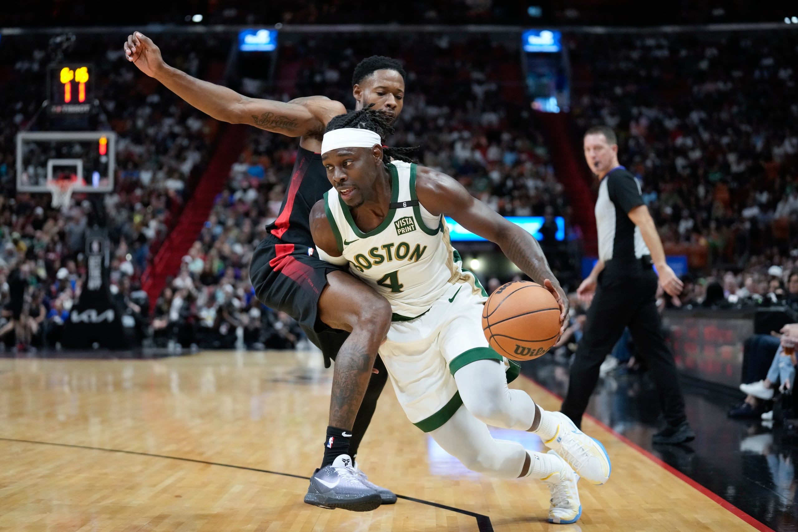 El base de los Celtics de Boston Jrue Holiday avanza hacia la canasta superando al alero del Heat de Miami Haywood Highsmith en el encuentro de la NBA del domingo.