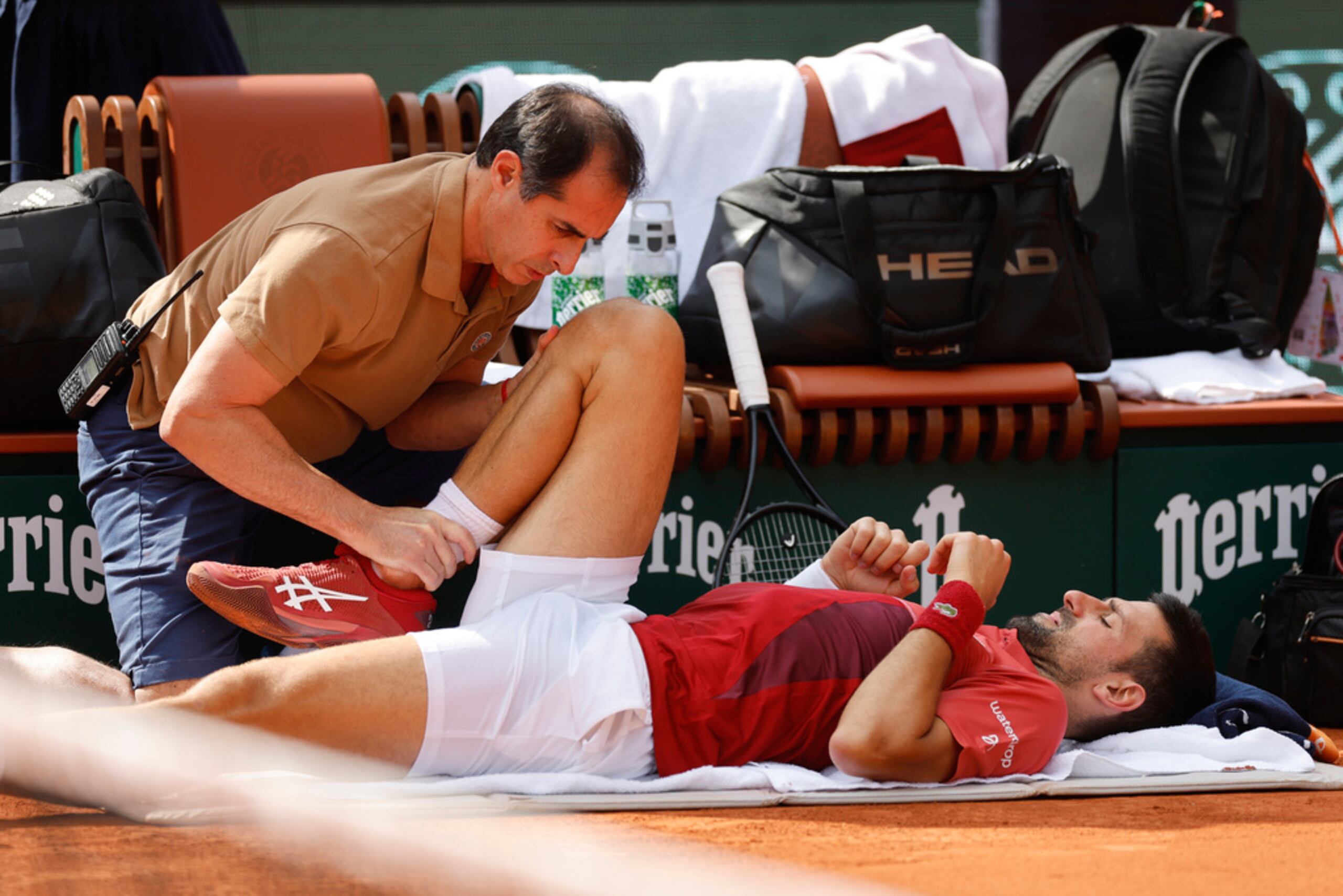 Novak Djokovic recibe asistencia médica en su rodilla derecha durante el partido contra Francisco Cerúndolo en los octavos de final del Abierto de Francia.