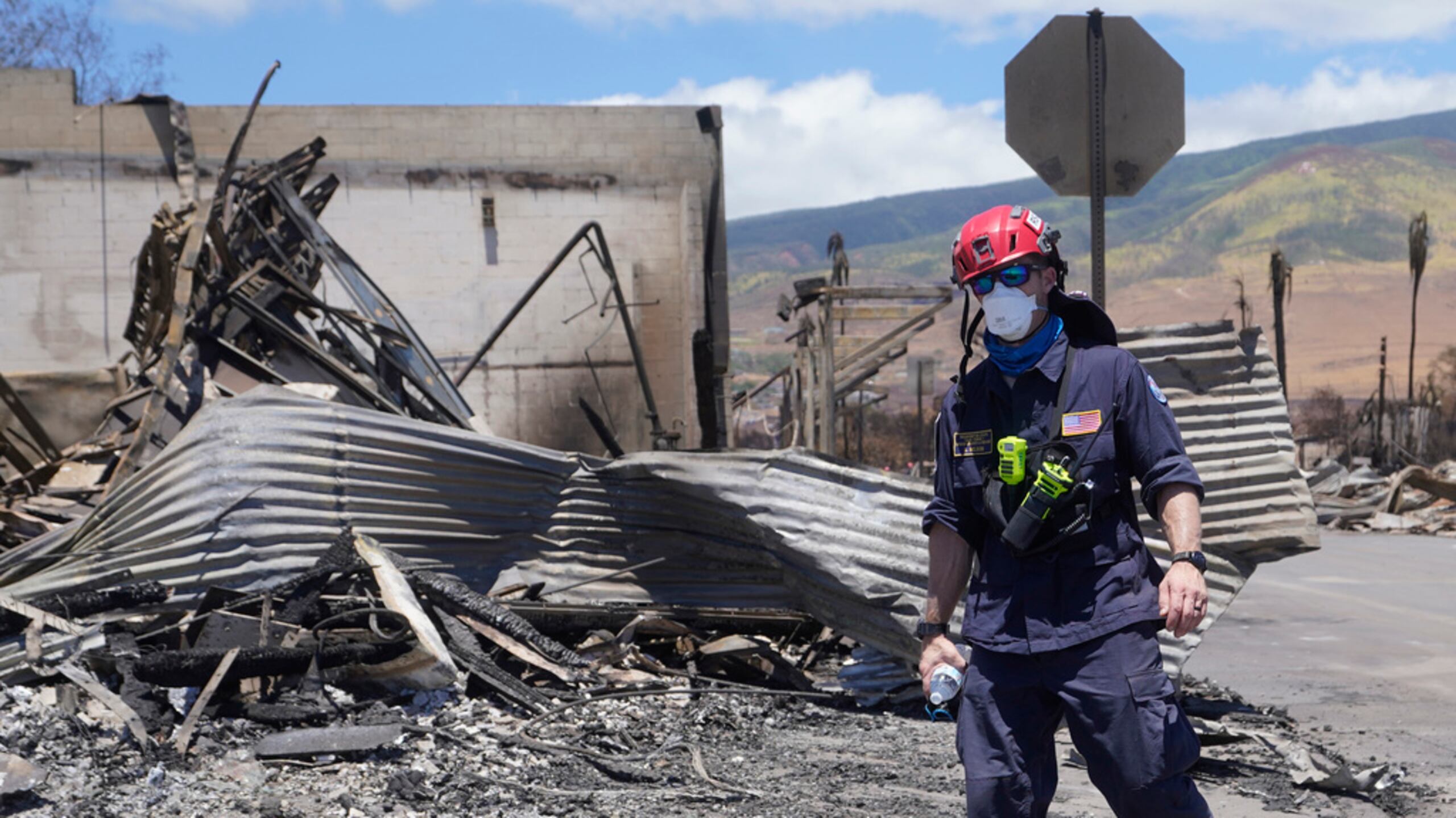 Un trabajador de búsqueda y rescate camina tras incendios forestales que causaron graves daños.