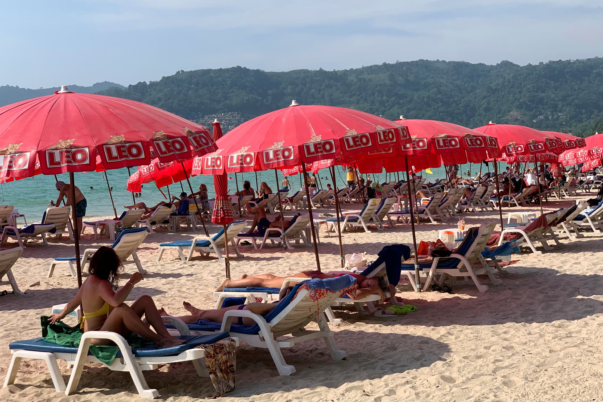 Turistas disfrutan baj sombrillas en la Playa Patong en Phuket (AP Foto/Salinee Prab)