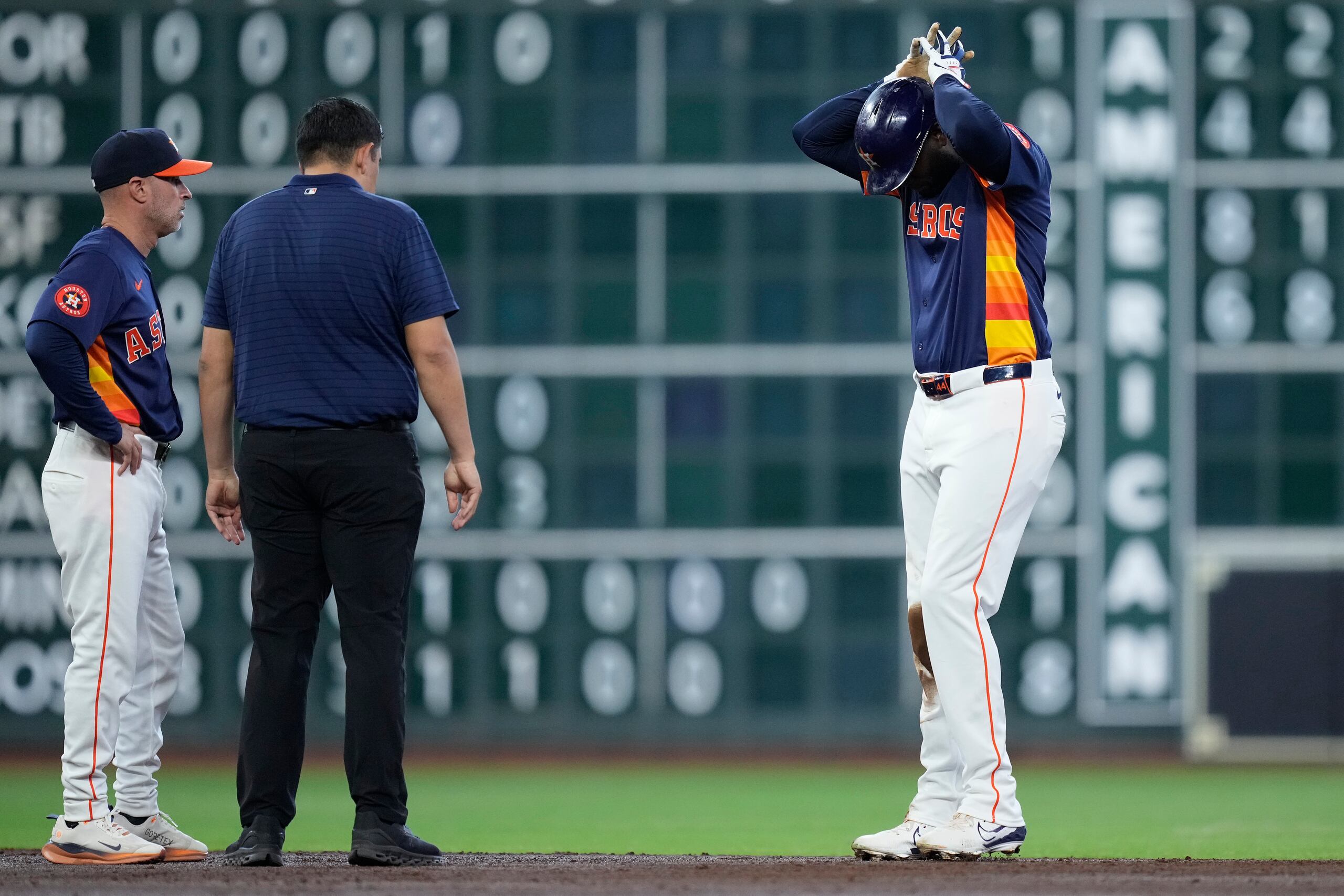 Yordan Álvarez, derecha, de los Astros de Houston, prueba su pierna derecha ante la mirada del mánager Joe Espada, izquierda, y un miembro del cuerpo médico del equipo después de sufrir una lesión al barrerse en segunda base durante la tercera entrada del juego de béisbol en contra de los Angels de Los Ángeles, el domingo 22 de septiembre de 2024.