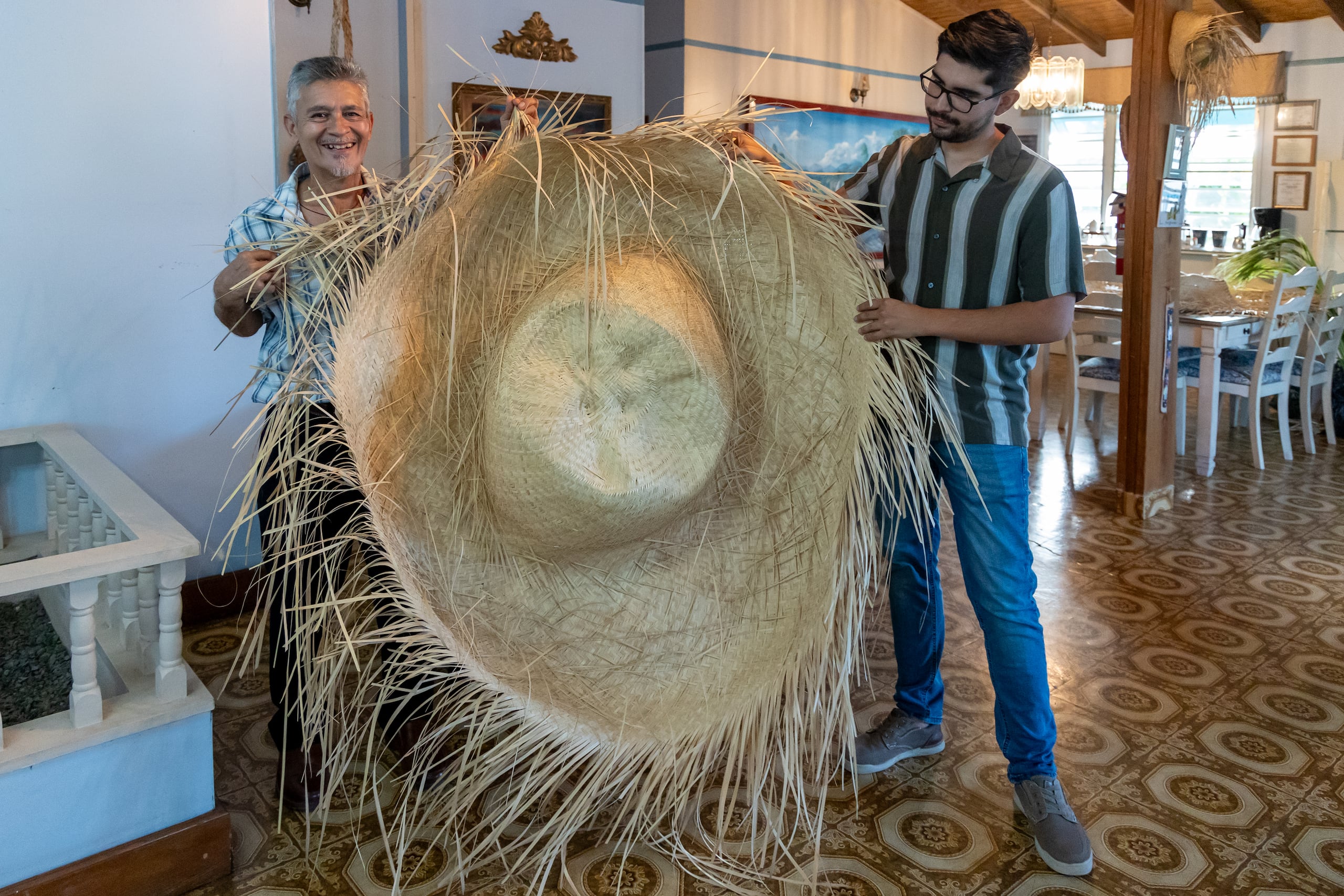 El artesano también es el encargado de confeccionar las enormes pavas de la Casa Azul en Aguada. En la foto junto a Christian Acevedo, director oficina de Turismo de ese municipio.