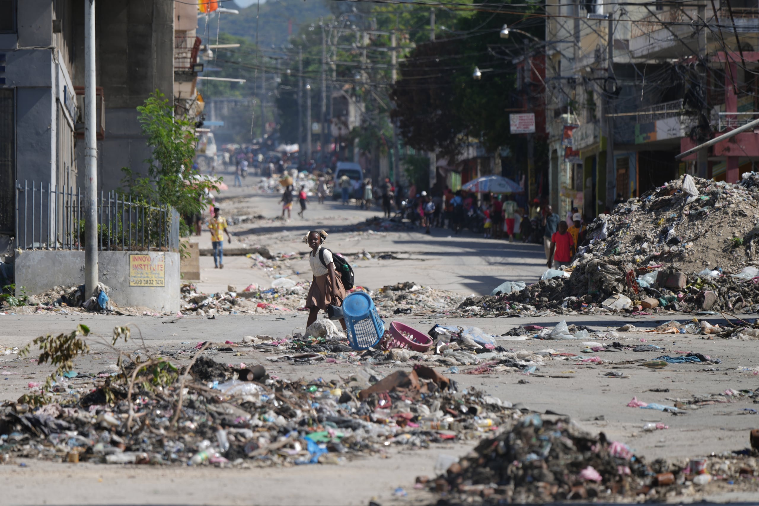 Una niña cruza una calle llena de basura en el centro de Puerto Príncipie, Haití, el martes 20 de enero de 2026. (AP Foto/Odelyn Joseph)