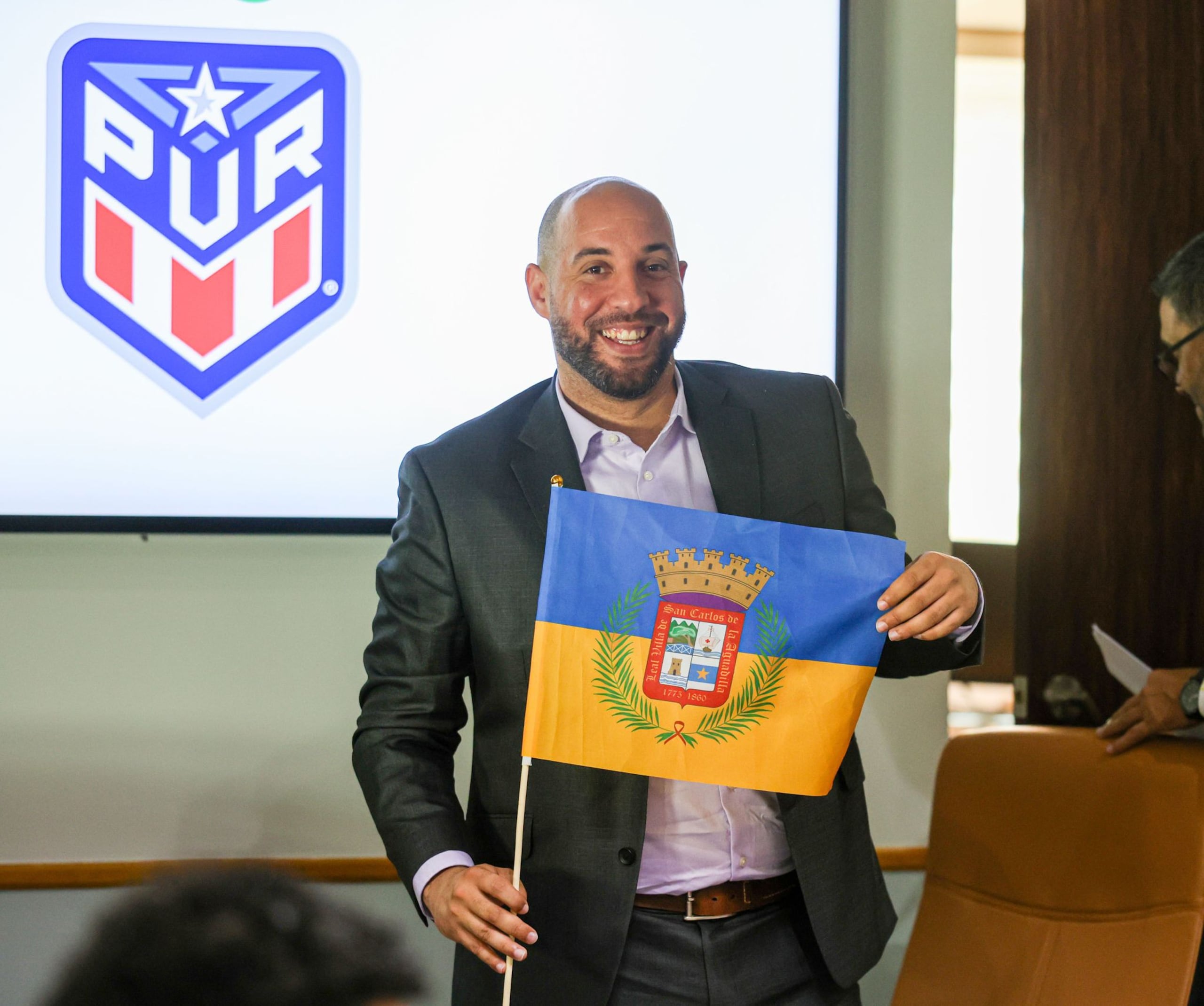 Carlos González enseña la bandera de su pueblo, Aguadilla, luego de ser nombrado dirigente de la Selección Nacional.