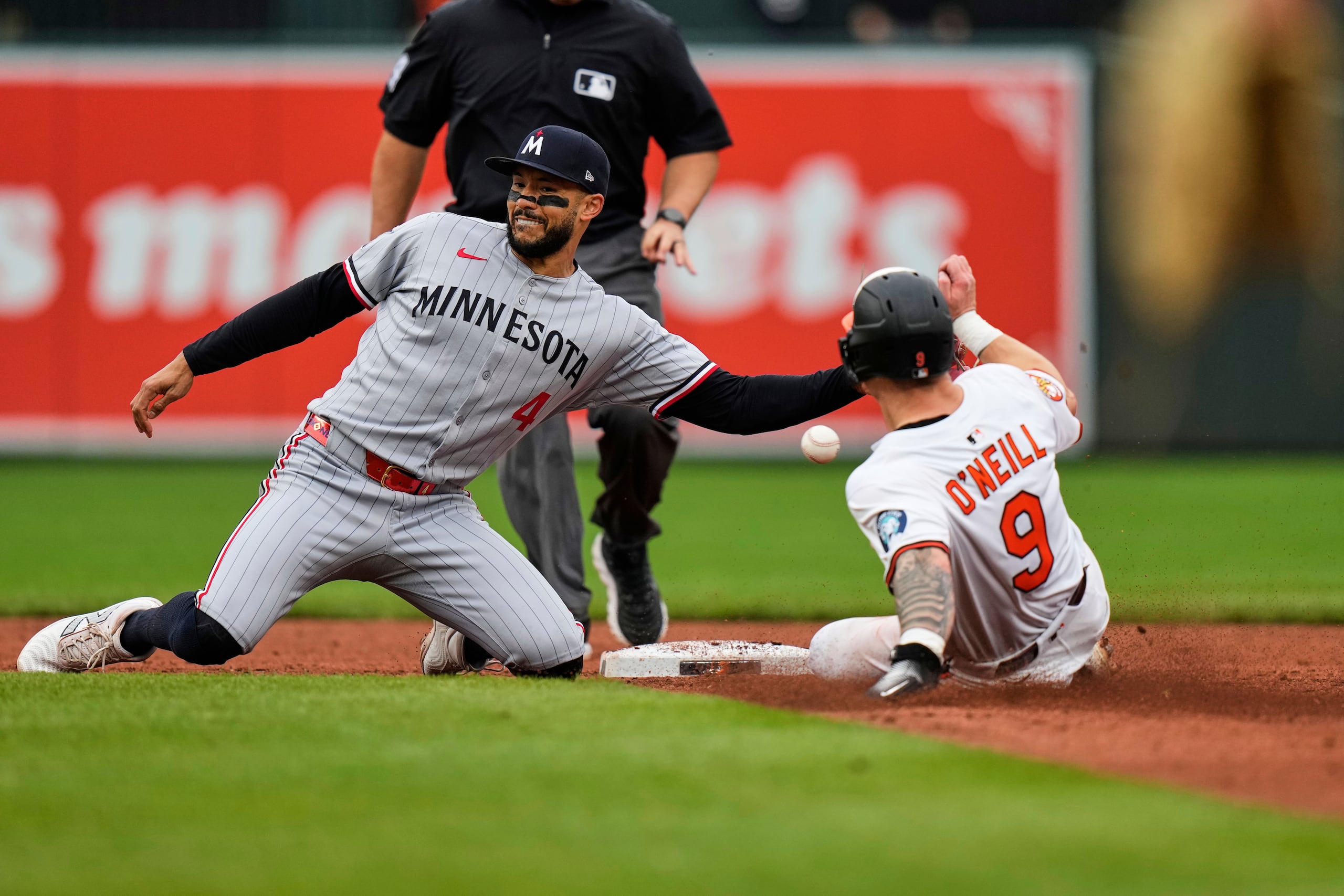 El boricua Carlos Correa, de los Twins de Minnesota, trata sin éxito de retirar a Tyler O'Neill, de los Orioles de Baltimore, en el juego del miércoles, 14 de mayo de 2025.