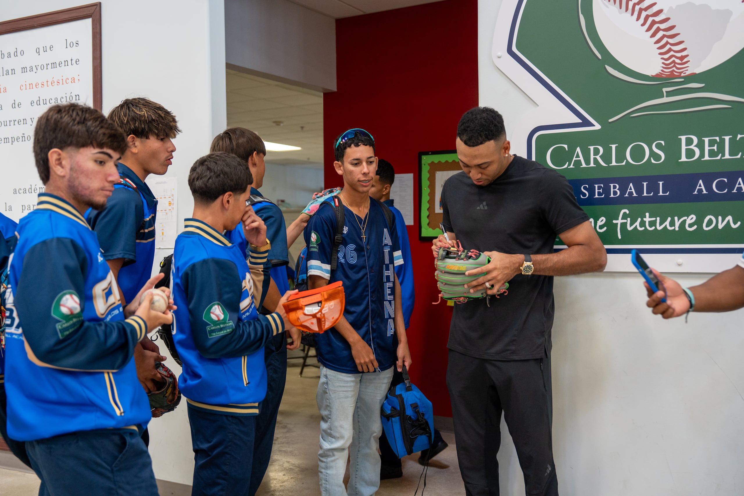 Edwin Díaz firma guantes a estudiantes de la Carlos Beltrán Baseball Academy durante una visita al plantel.