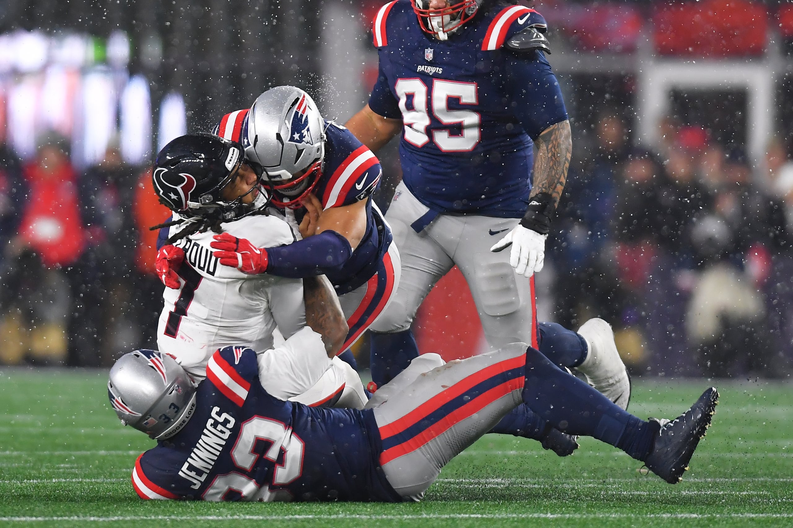 El quarterback C.J. Stroud (7), de los Texans de Houston, es derribado por Anfernee Jennings, abajo, y Christian Elliss, de los Patriots de Nueva Inglaterra, durante la segunda mitad del partido de la ronda divisional de los playoffs de la NFL, el domingo 18 de enero de 2026, en Foxborough, Massachusetts. (AP Foto/Steven Senne)