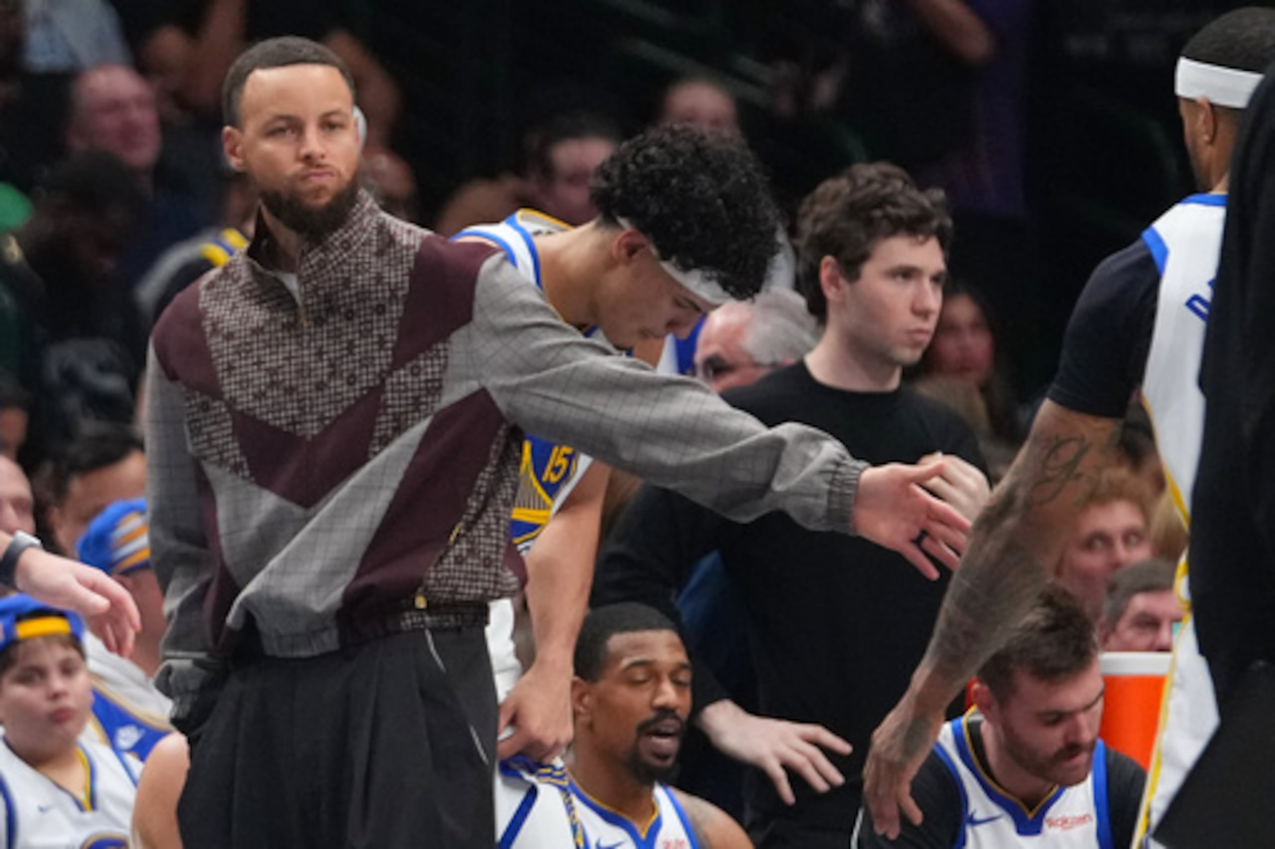 El escolta de los Golden State Warriors Stephen Curry viste ropa de calle mientras permanece cerca del banquillo de su equipo durante un tiempo muerto contra los Dallas Mavericks en la primera mitad de un partido de baloncesto de la NBA el lunes 23 de marzo de 2026, en Dallas. (AP Photo/Julio Cortez)