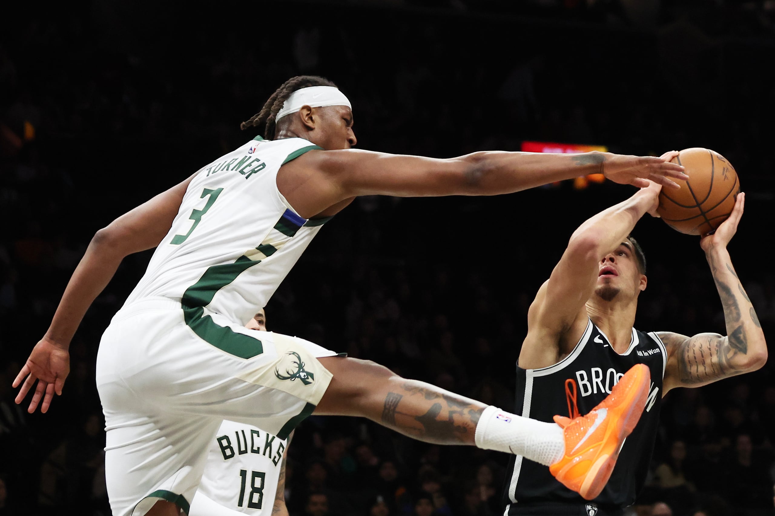 El alero de los Nets de Brooklyn, Michael Porter Jr., levanta en el aire al pívot de los Bucks de Milwaukee, Myles Turner (3), mientras conduce hacia la canasta durante la primera mitad de un juego de baloncesto de la NBA, el domingo 14 de diciembre de 2025, en Nueva York. (AP Photo/Heather Khalifa)