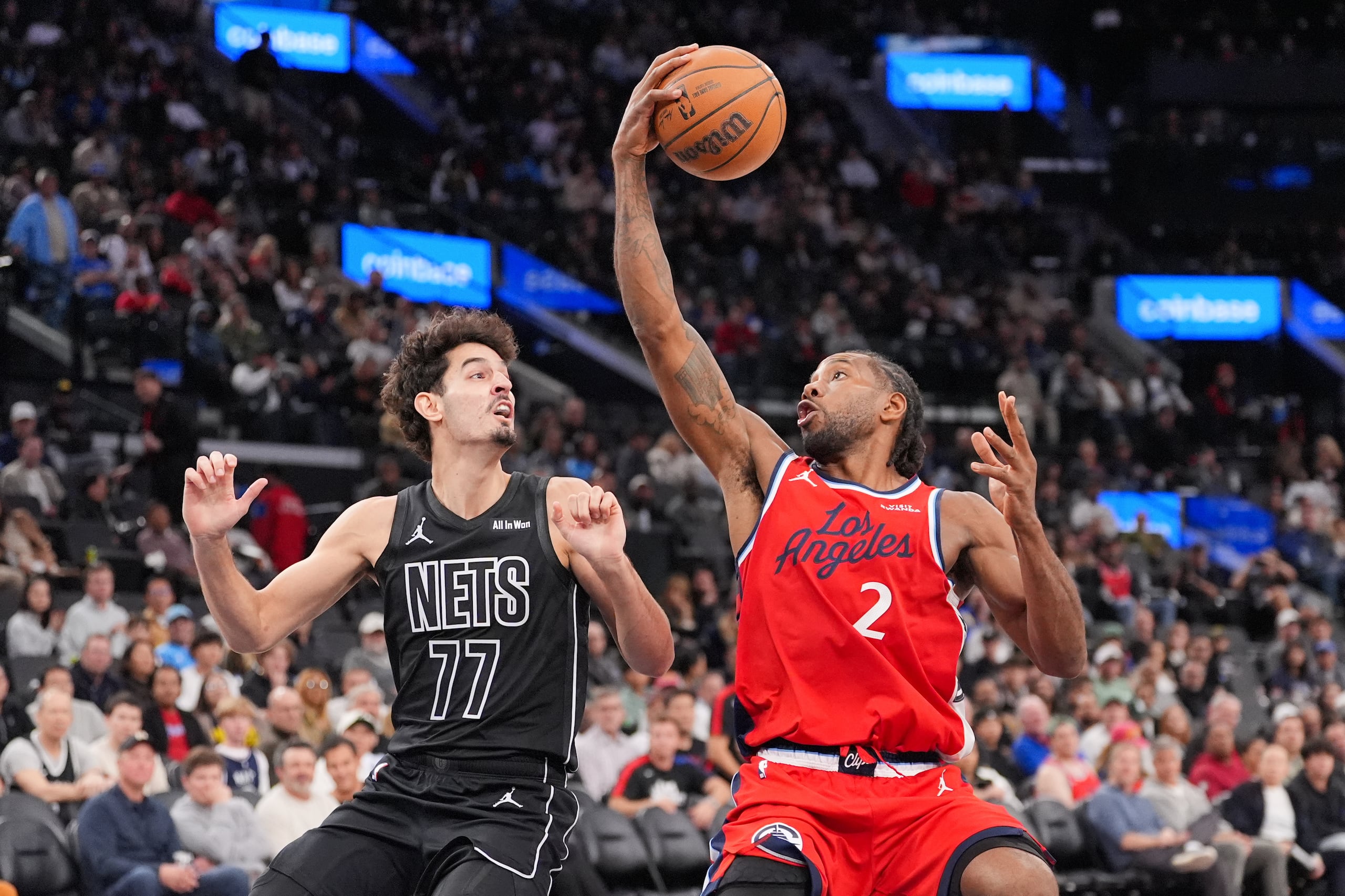 Kawhi Leonard (2), de los Clippers de Los Ángeles, hace una finta de un tiro frente a Ben Saraf (77), de los Nets de Brooklyn, durante la segunda mitad del juego de baloncesto de la NBA, el domingo 25 de enero de 2026, en Inglewood, California. (AP Foto/Jae C. Hong)