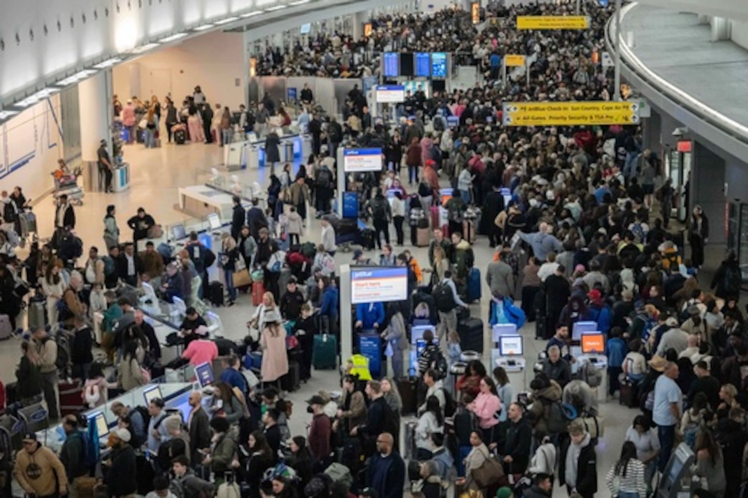 Varias personas esperan en una cola de la TSA en el Aeropuerto Internacional John F. Kennedy, el domingo 22 de marzo de 2026, en Nueva York. (AP Photo/Yuki Iwamura)