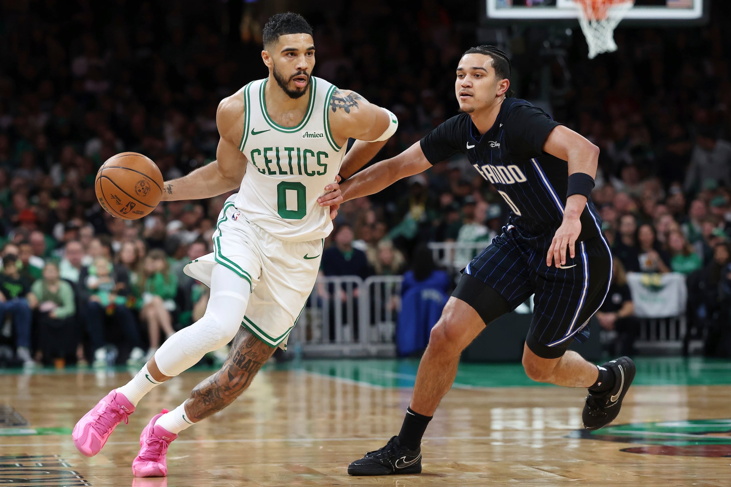 Jayson Tatum, de los Celtics de Boston, a la izquierda, pasa junto a Anthony Black, del Magic de Orlando, durante la primera mitad del primer partido de una serie de baloncesto de primera ronda de los playoffs de la NBA, el domingo 20 de abril de 2025, en Boston. (AP Foto/Michael Dwyer)
