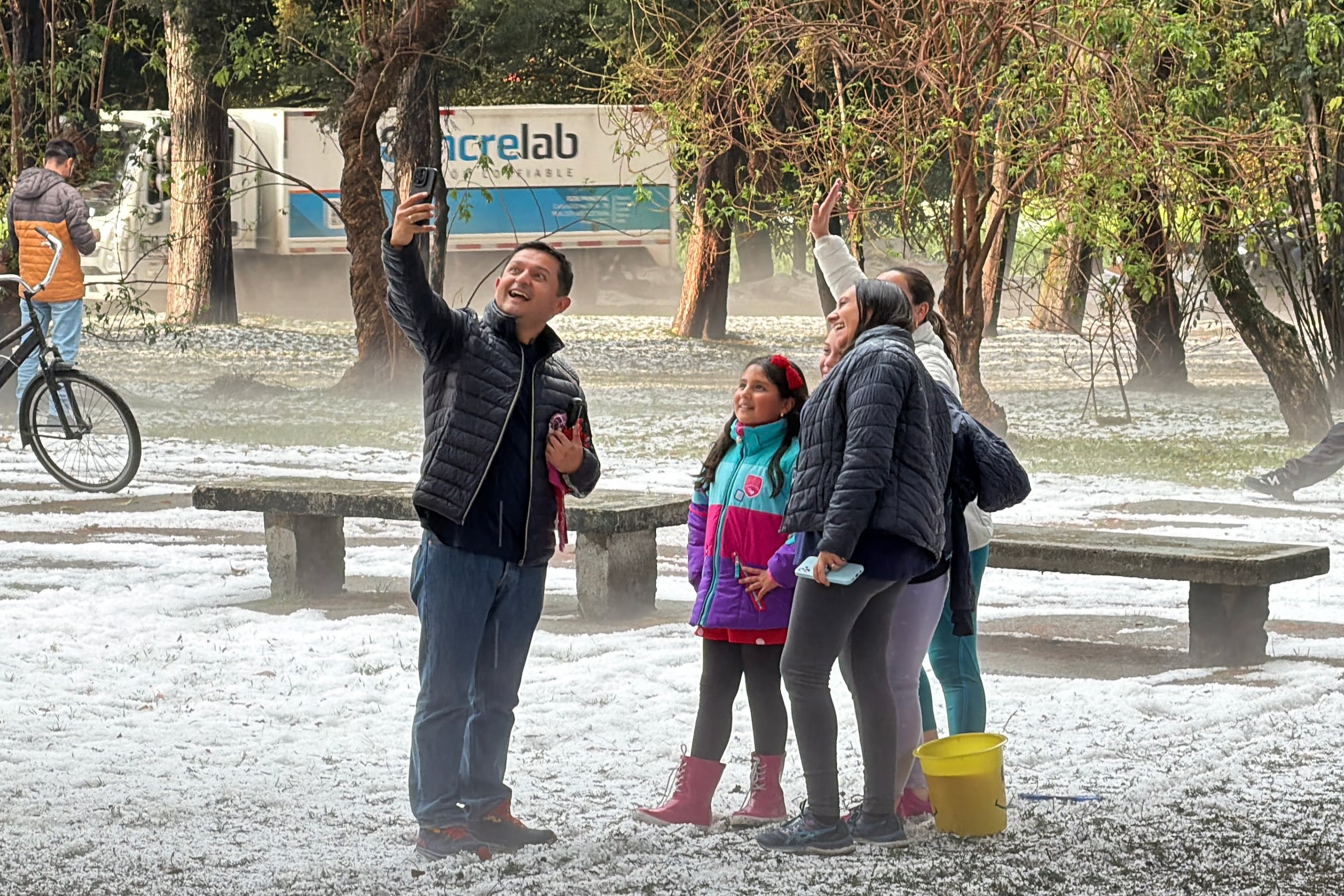 Un grupo de personas fue captado este 5 de octubre al posar para una fotografía en un parque cubierto de granizo en Bogotá (Colombia). EFE/Juan Diego López
