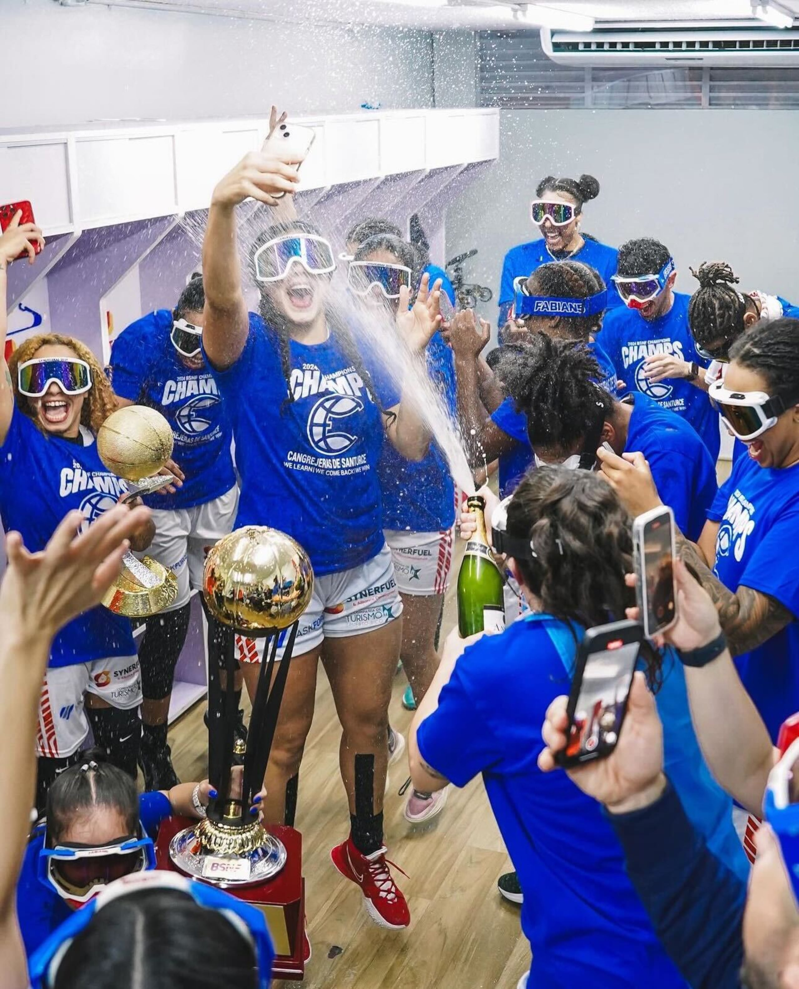 Las Cangrejeras de Santurce celebran con champán en el camerino visitante del Coliseo Guillermo Angulo, de Carolina.